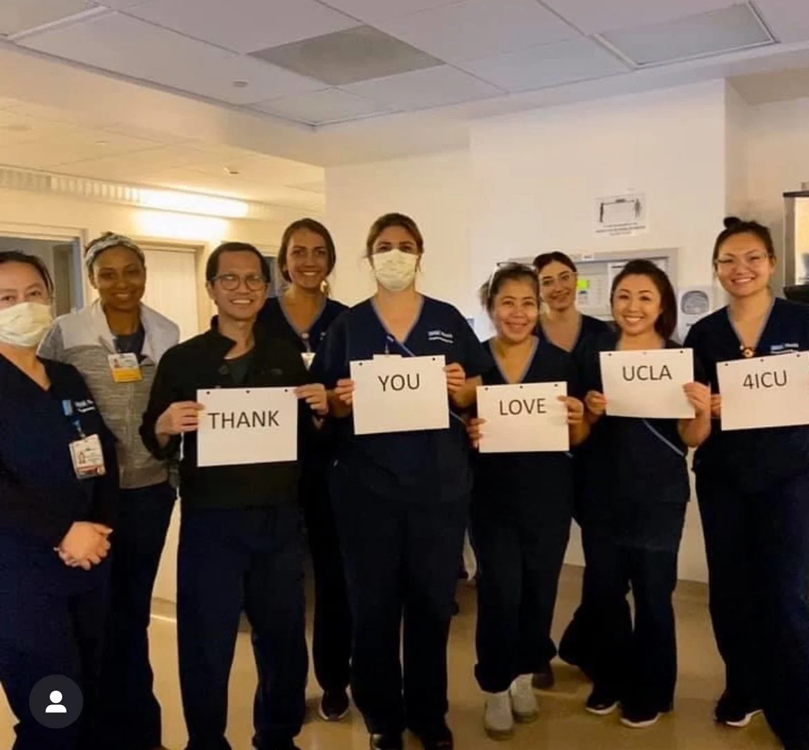 Group of healthcare workers holding signs that spell out "Thank You Love UCLA 4 ICU" in a hospital setting.