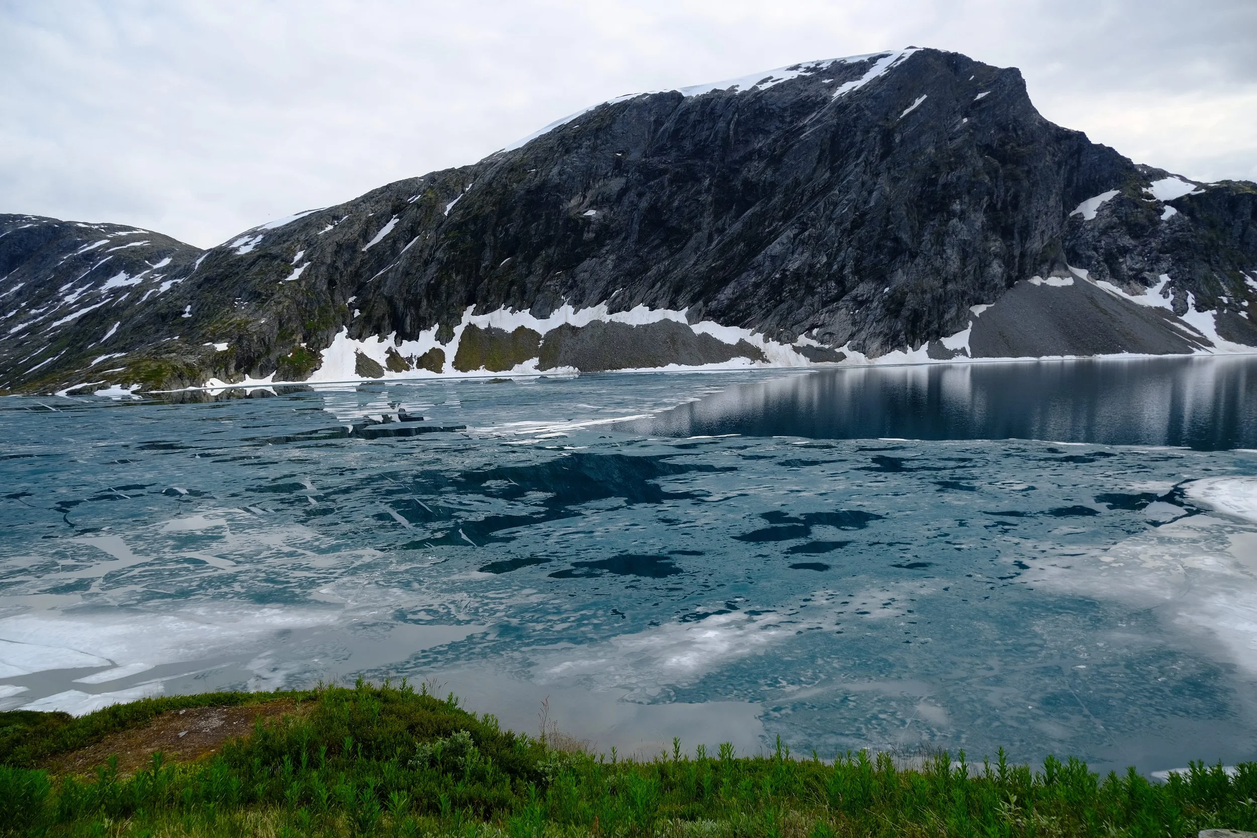 Gletschersee mit Eis und schneebedeckten Bergen im Hintergrund in Norwegen