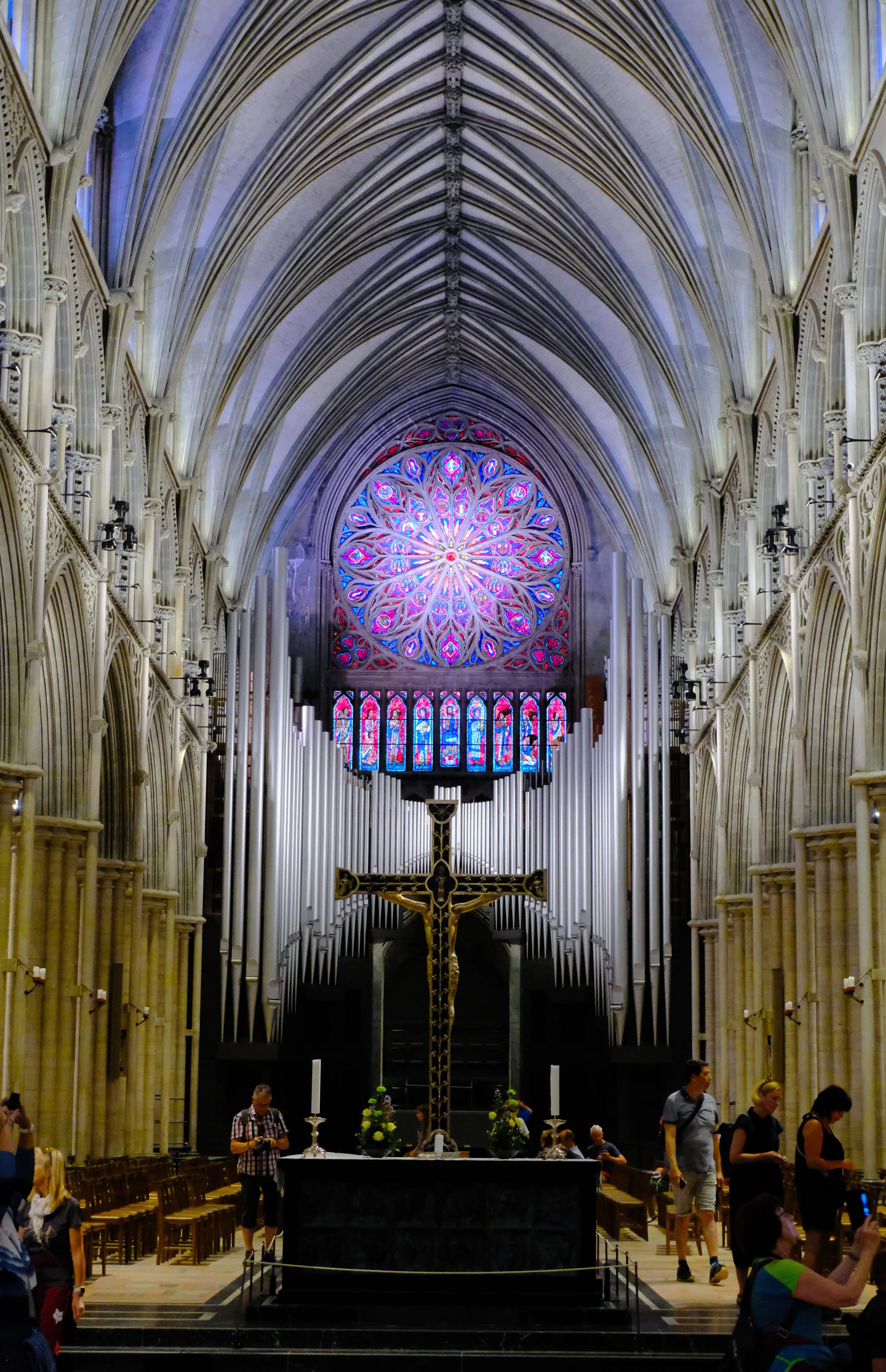 Innenansicht einer gotischen Kathedrale mit Altar, Kreuz, und buntem Kirchenfenster