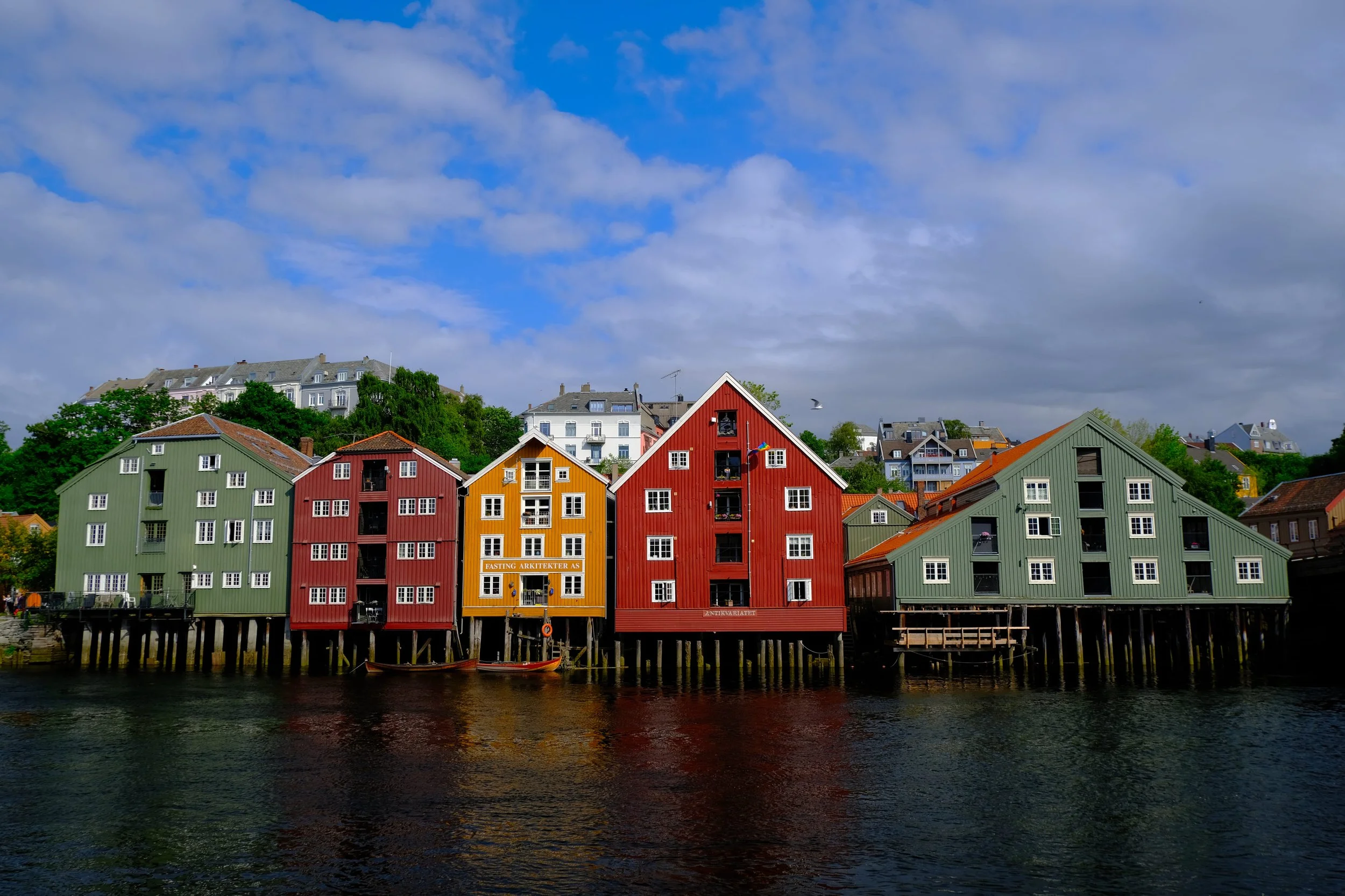 Bunte Häuser an einem Wasserarm, mit Himmel und Wolken im Hintergrund.