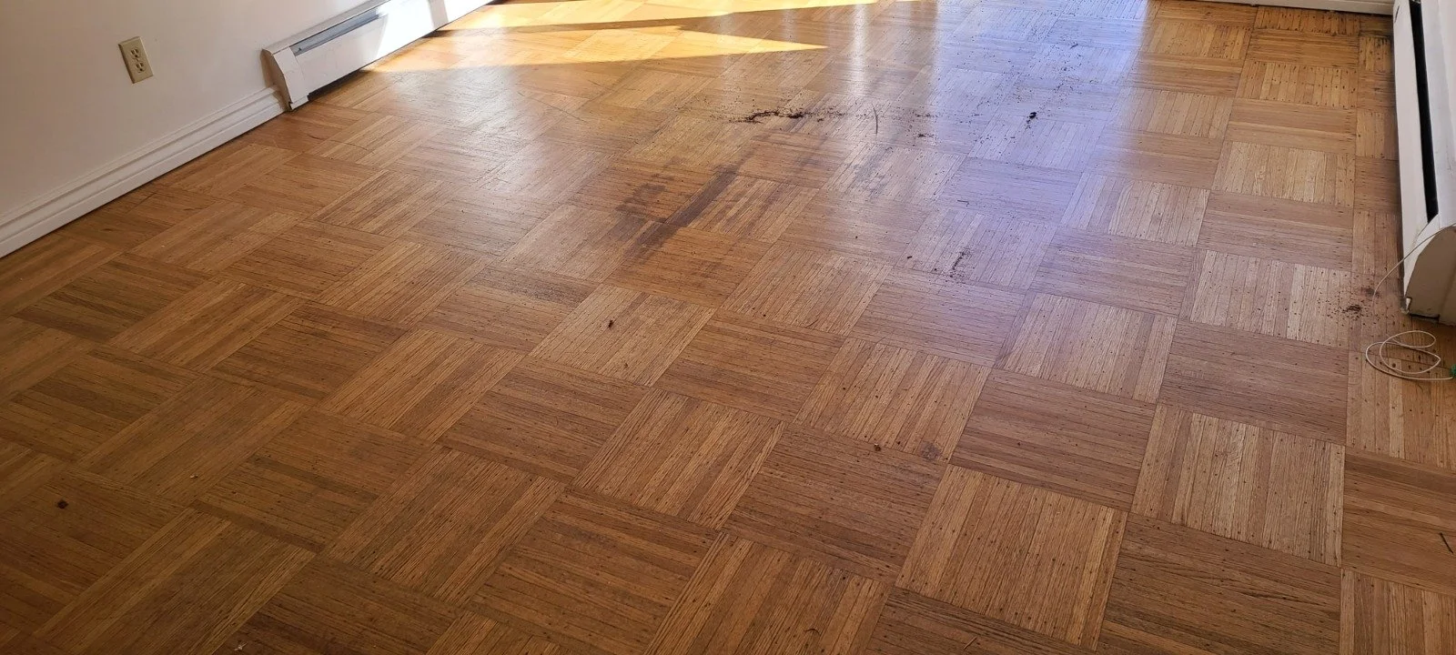 Room with hardwood flooring, some marks, and a wall heater