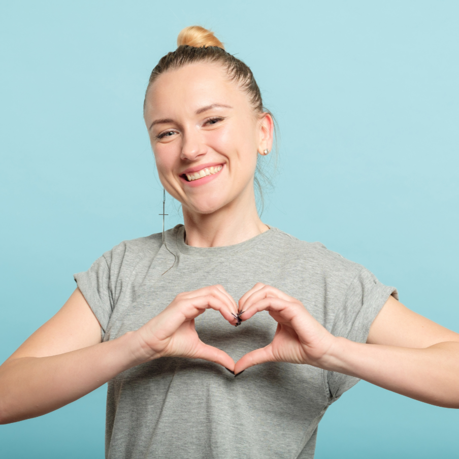 Happy young woman making a heart shape with her hands