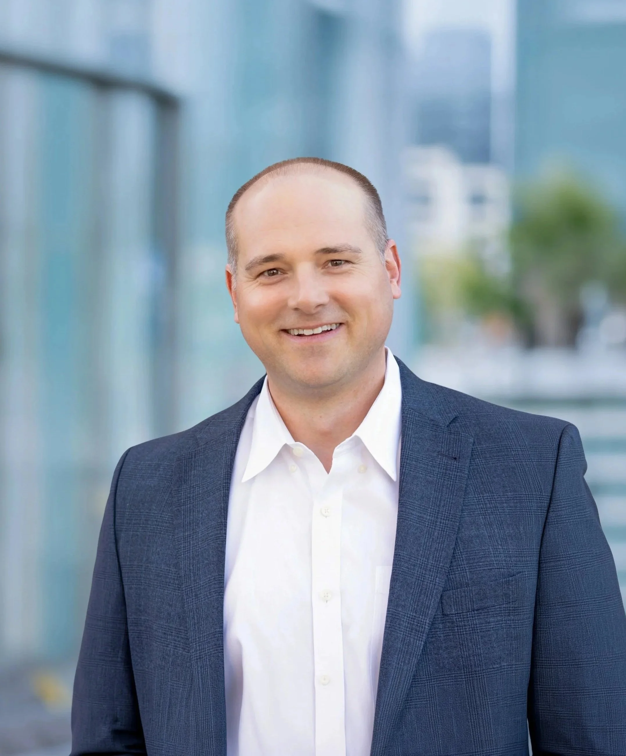 A smiling bald man in a suit with a blazer jacket