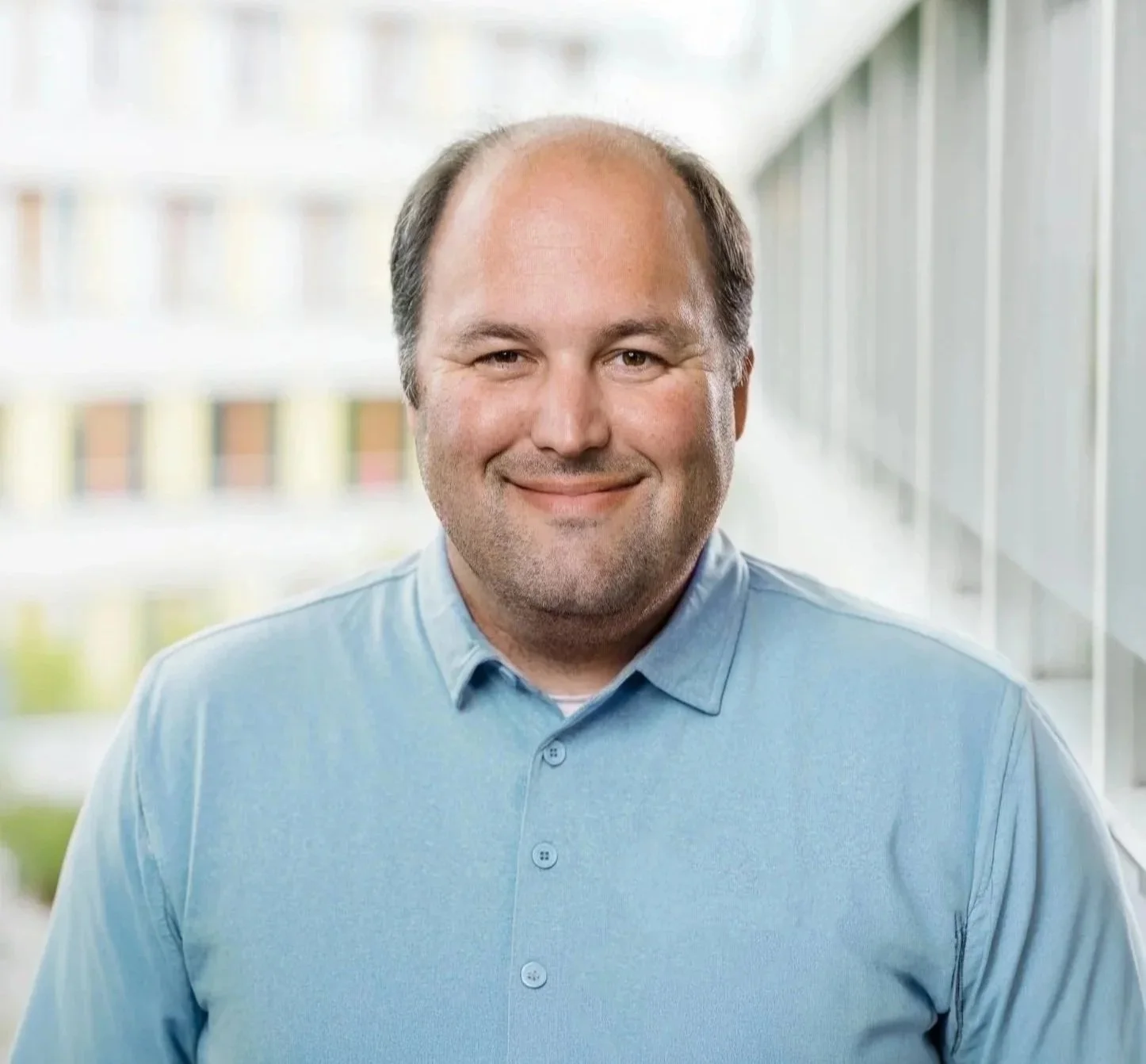 A smiling bald man in a blue polo