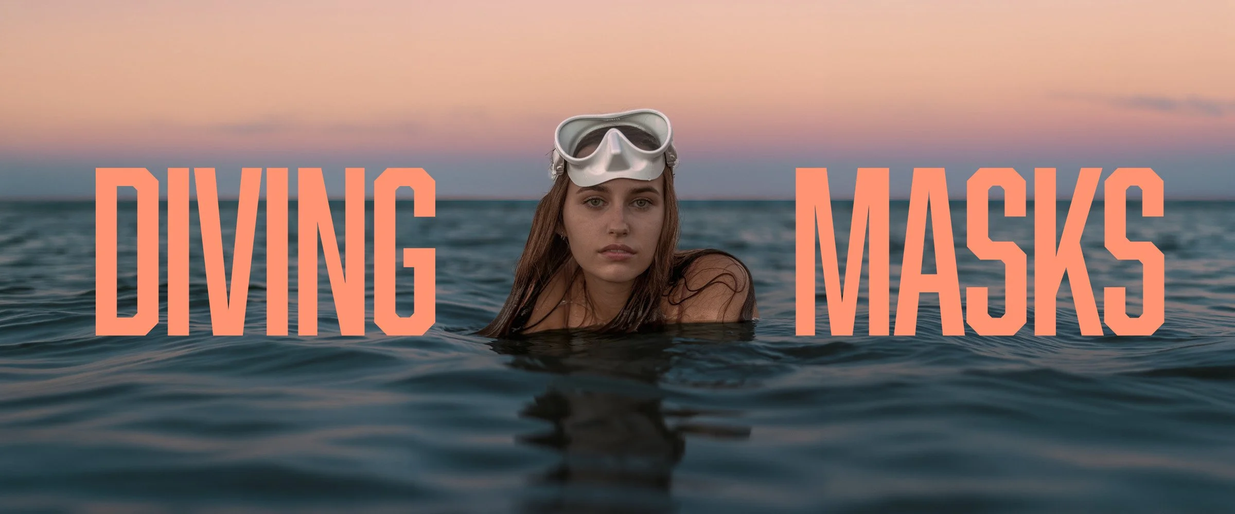 A swimmer wearing a white dive mask at sunset, with coral DIVING MASKS lettering.