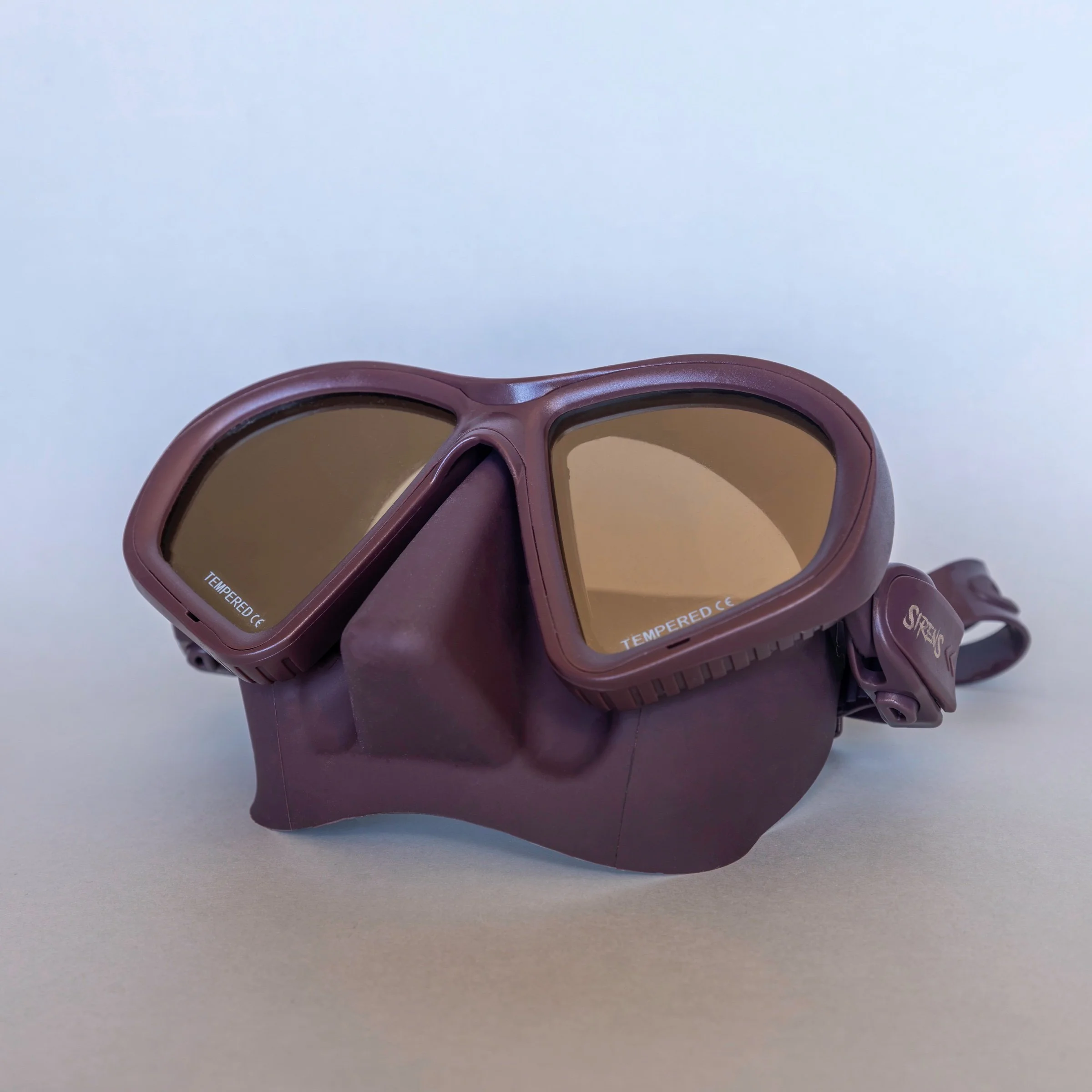 Natural Sirens dive mask with a dark brown frame and reflective lenses, photographed on a neutral background.