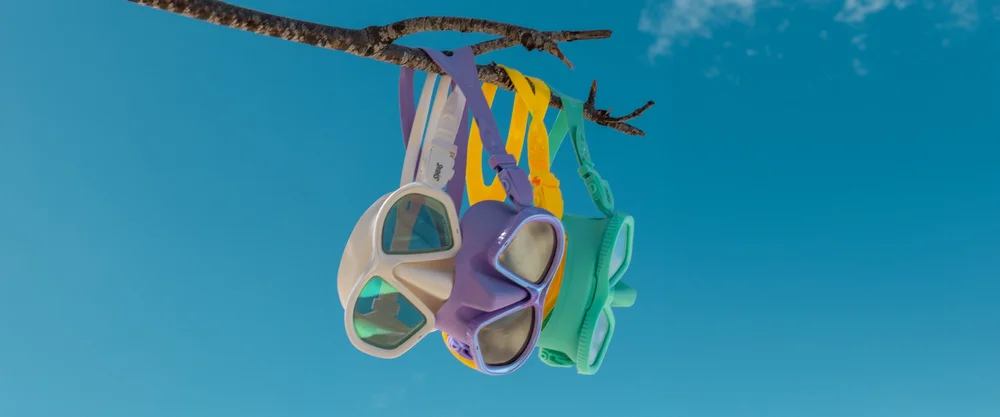 Colourful Sirens dive masks hanging against a blue sky.
