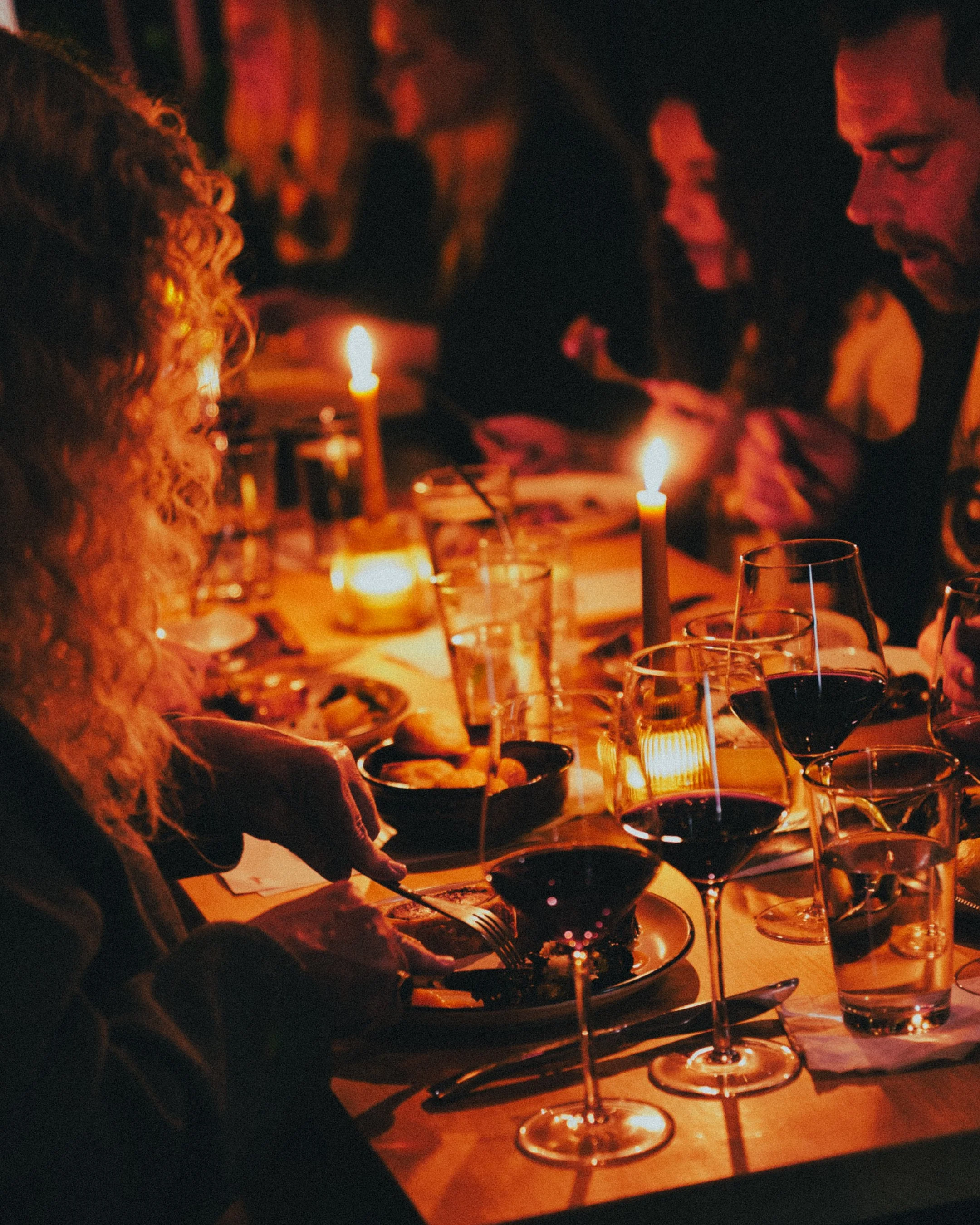 guests sitting around a candle lit table with wine