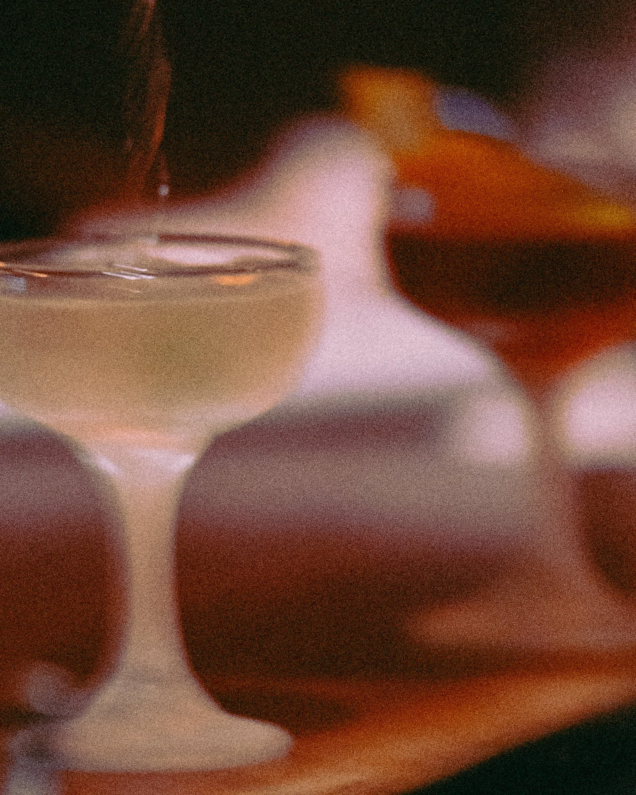 Close-up of a glass of white wine with blurred red and yellow objects in the background.