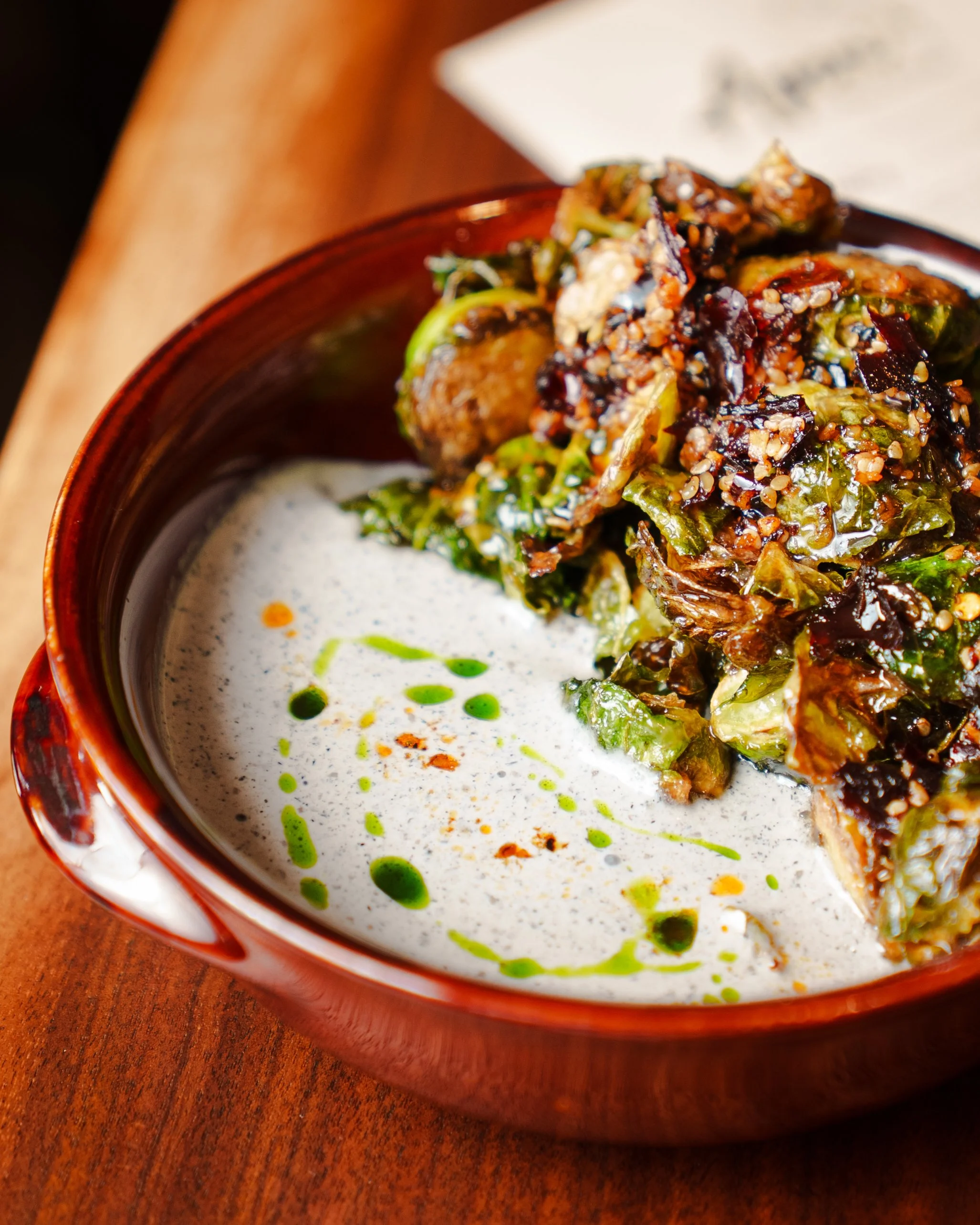Close-up of fried brussels sprouts with black sesame foam, sunflower seed caramel, and salsa seca