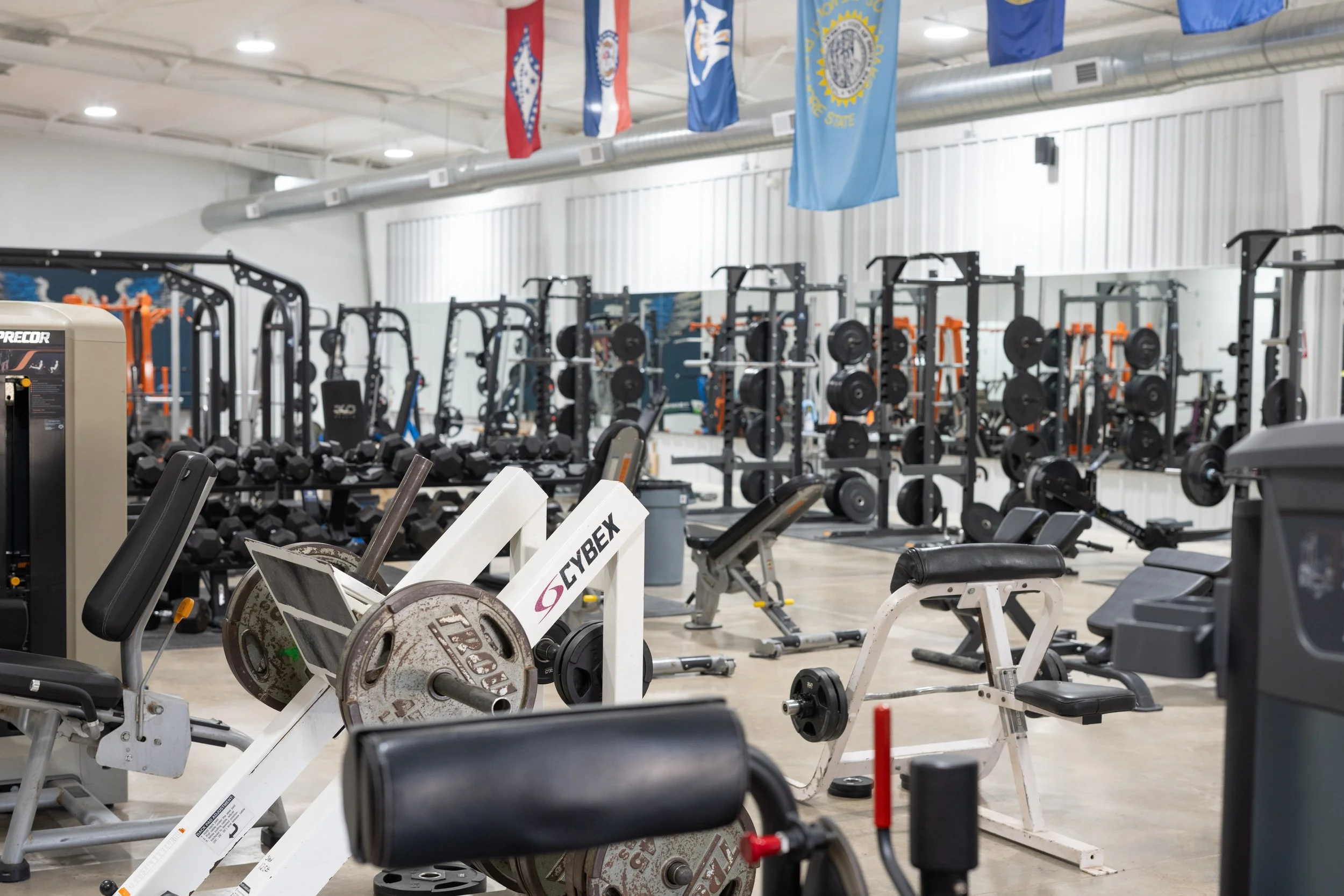 Commercial grade fitness equipment installed at a modular workforce housing facility, including cable machines, squat racks,  bench press areas, large dumbbell selection, and treadmills.