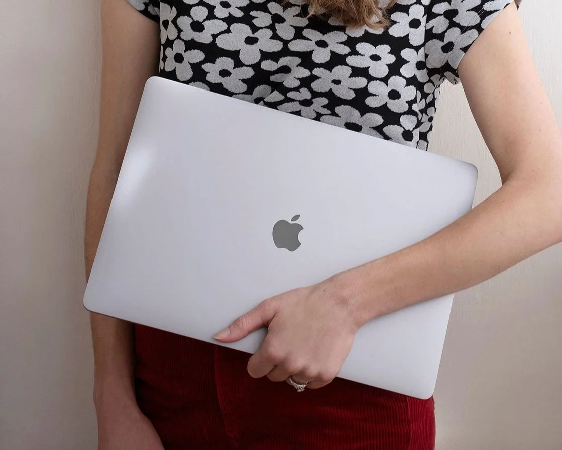 Closeup of Alyssa Downey's arm holding an Apple laptop.