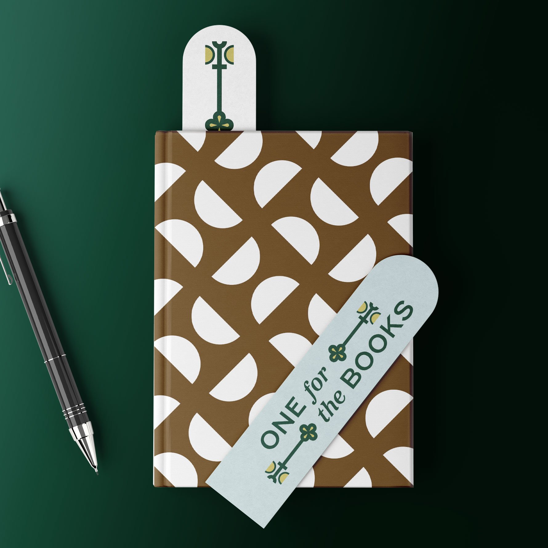 One for the Books logo design on a bookmark, on top of a notebook printed with a custom retro brand pattern design