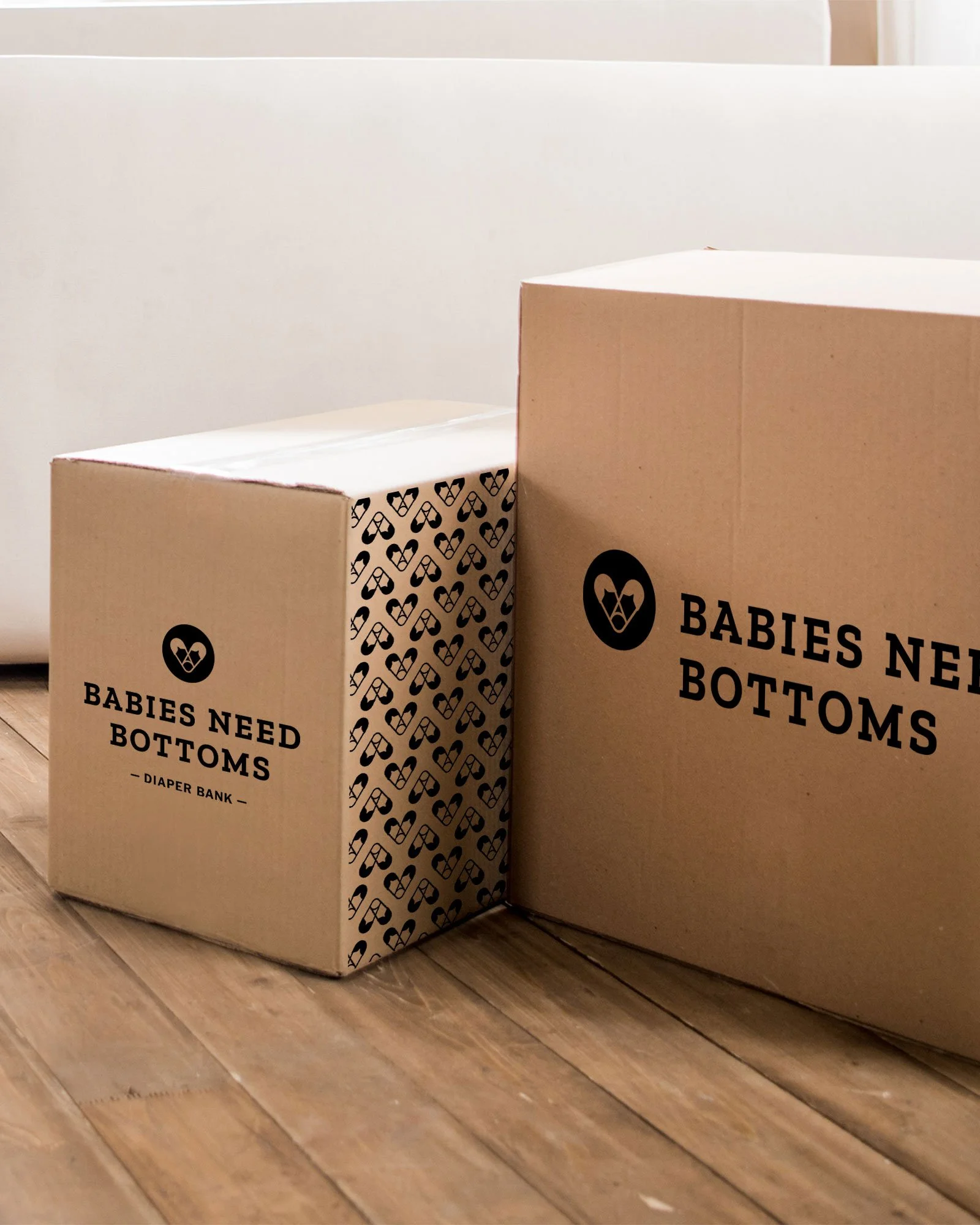 Logo design for Babies Need Bottoms, a Western NC diaper bank, shown on cardboard boxes