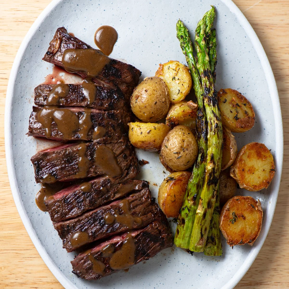 A plate of coffee seasoned grilled steak topped, roasted mini potatoes, and grilled asparagus.