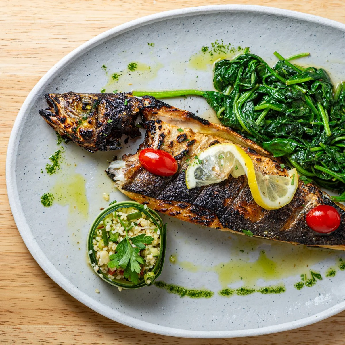 Grilled fish with lemon slices and cherry tomatoes, paired with sautéed greens
