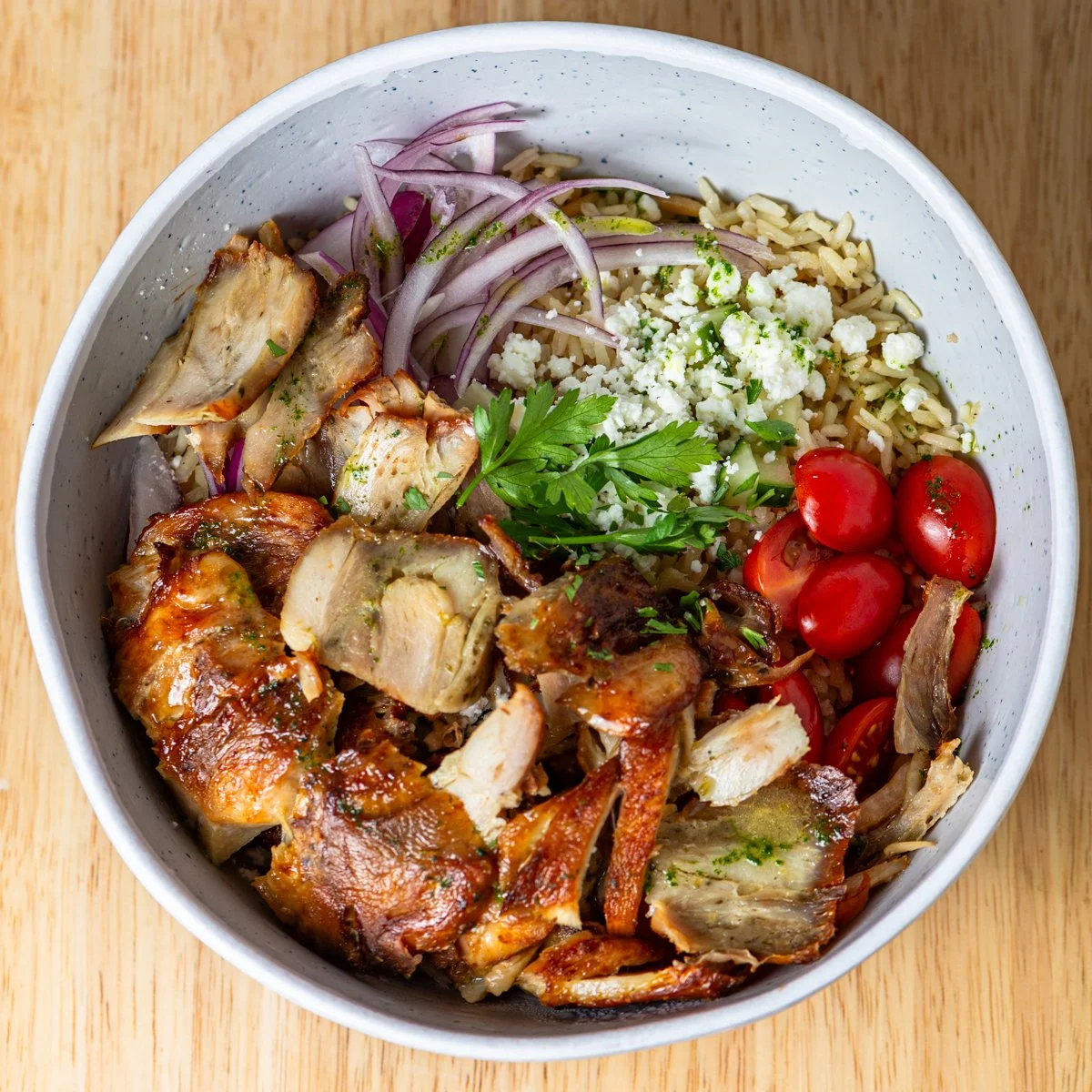 Casual Bowl with grilled chicken, cherry tomatoes, red onions, crumbled cheese, and spices