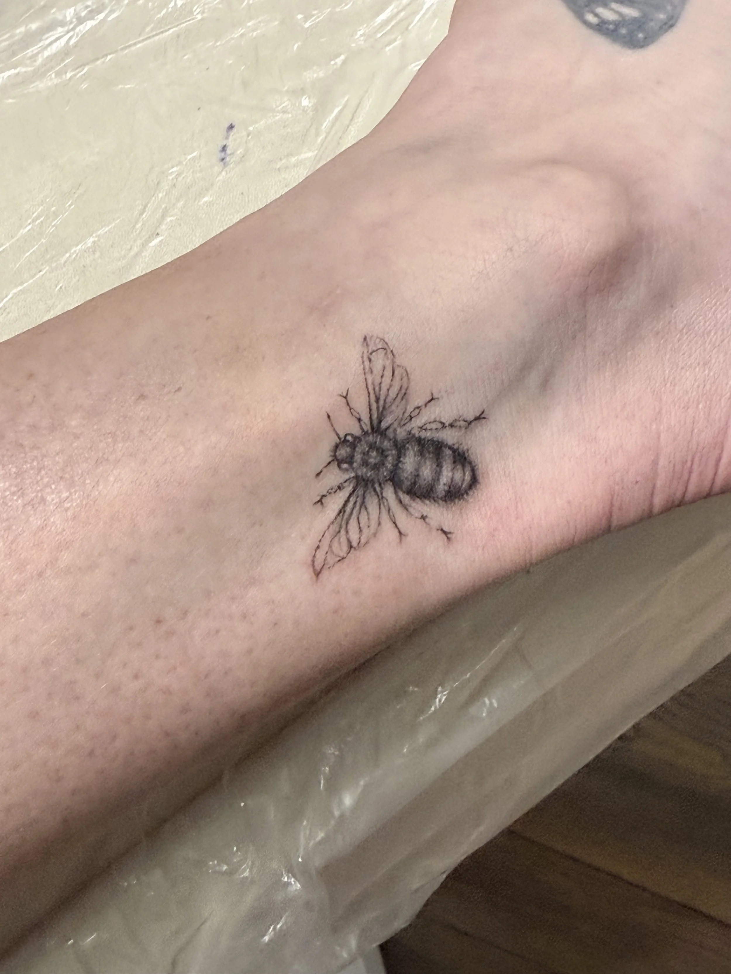 Tattoo of a bee on a person's wrist.
