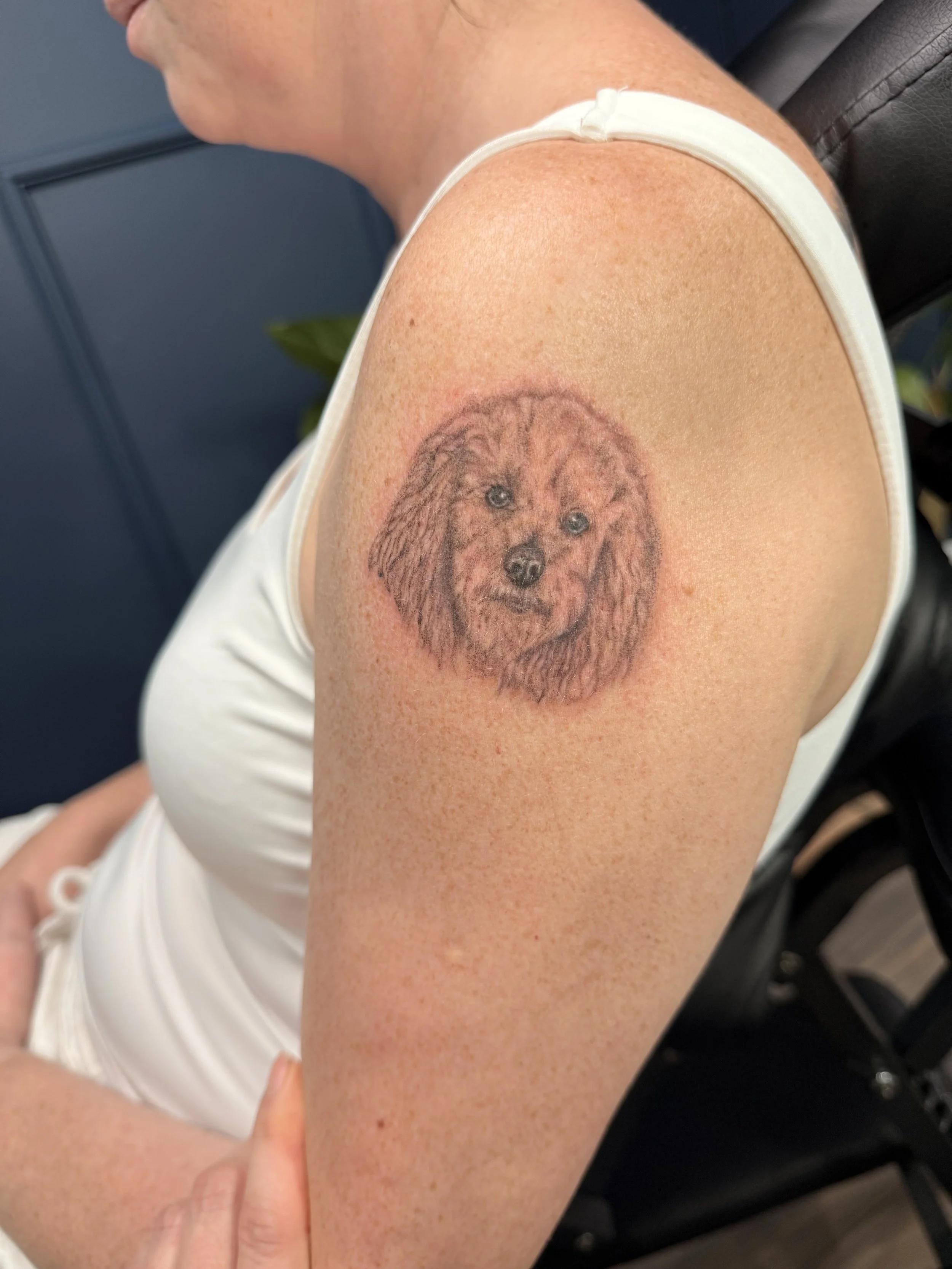 Tattoo of a dog's face on a person's upper arm.