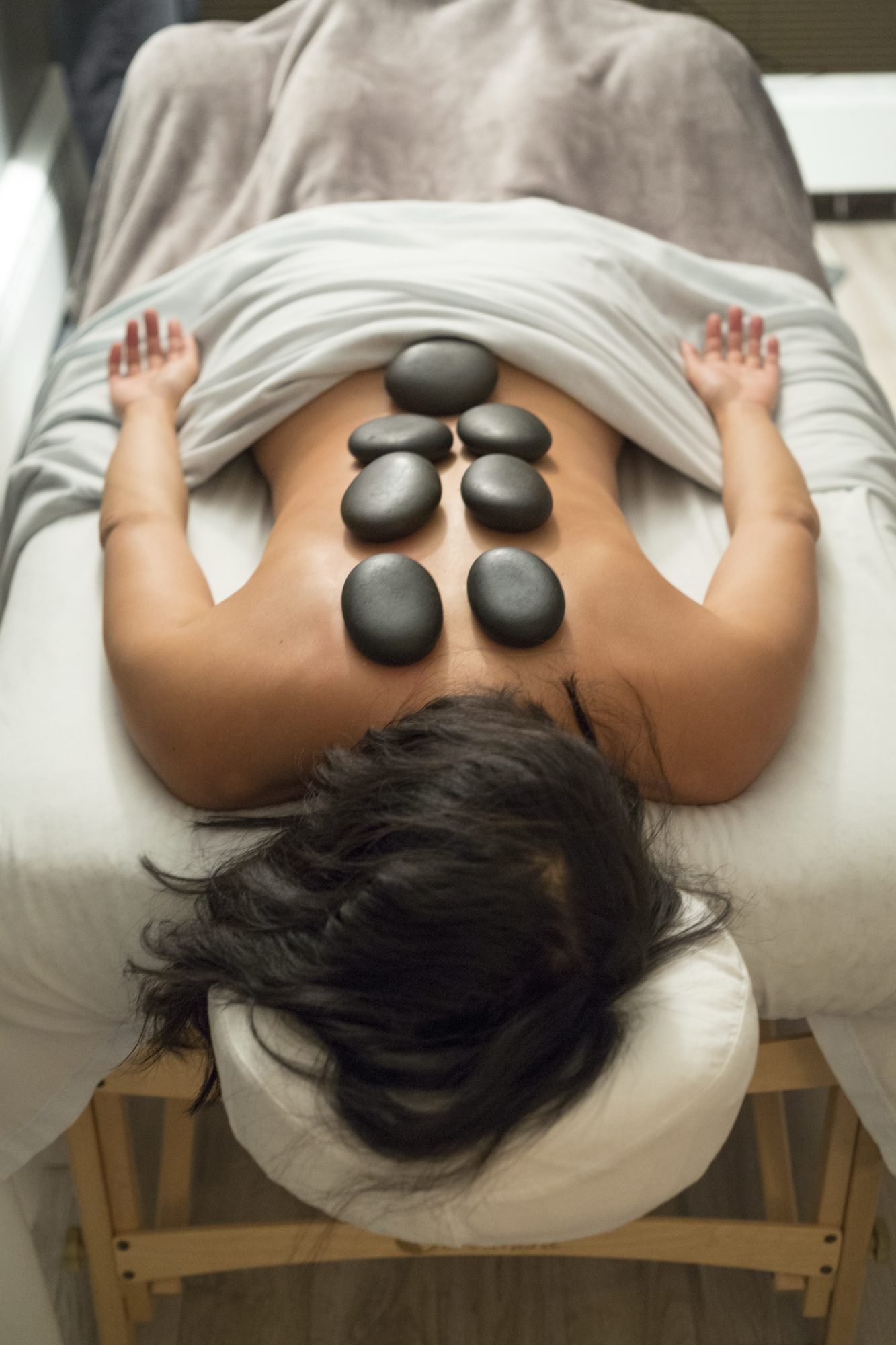 Smooth hot stones placed along a client’s back during a hot stone massage