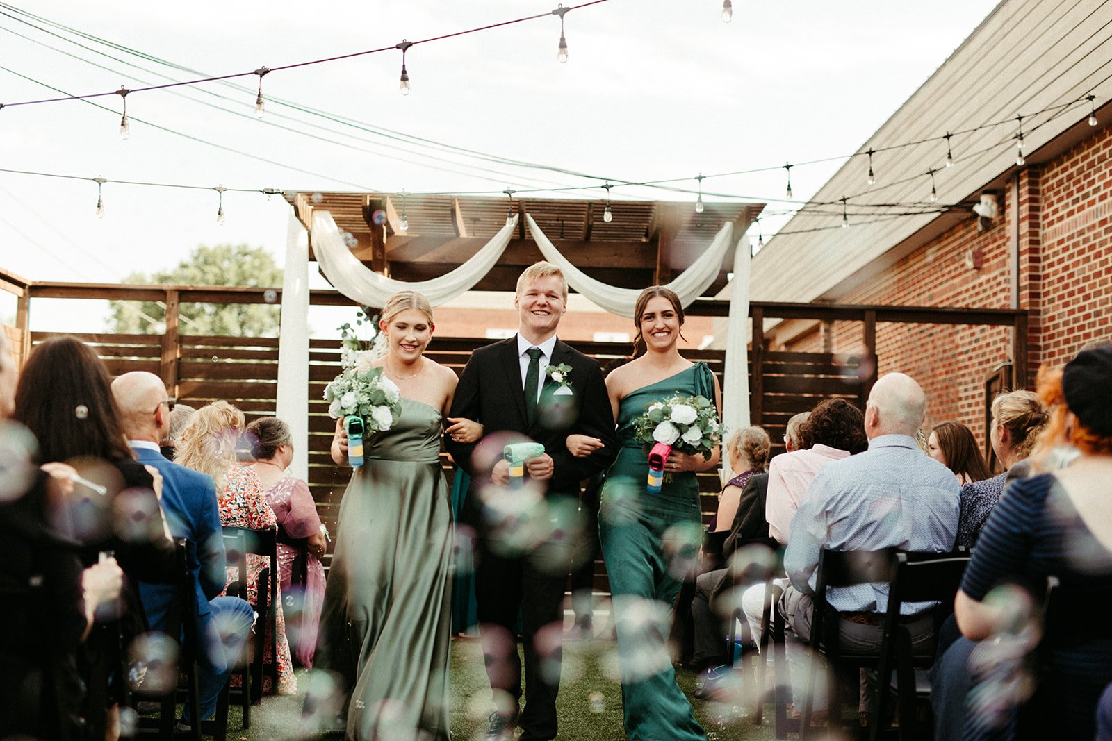 The wedding party recesses up the courtyard aisle through a flurry of bubbles at 8th & Main.