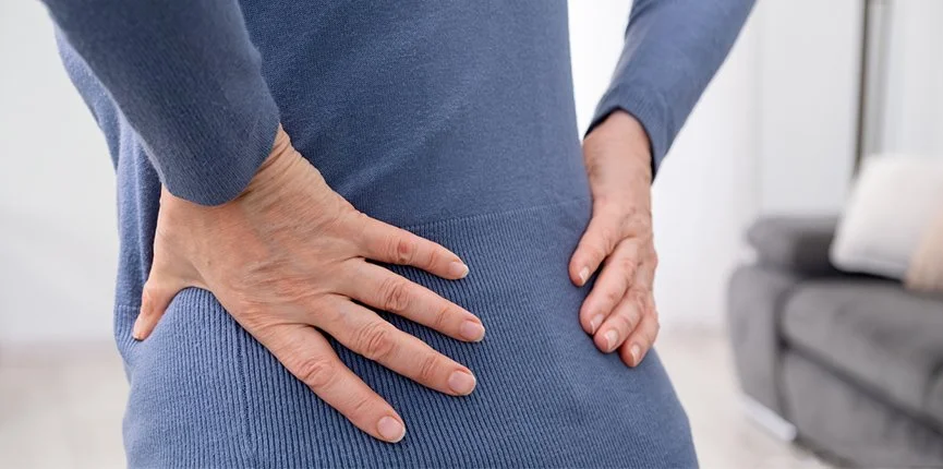 Woman viewed from the back holding both sides of her lower back and hips