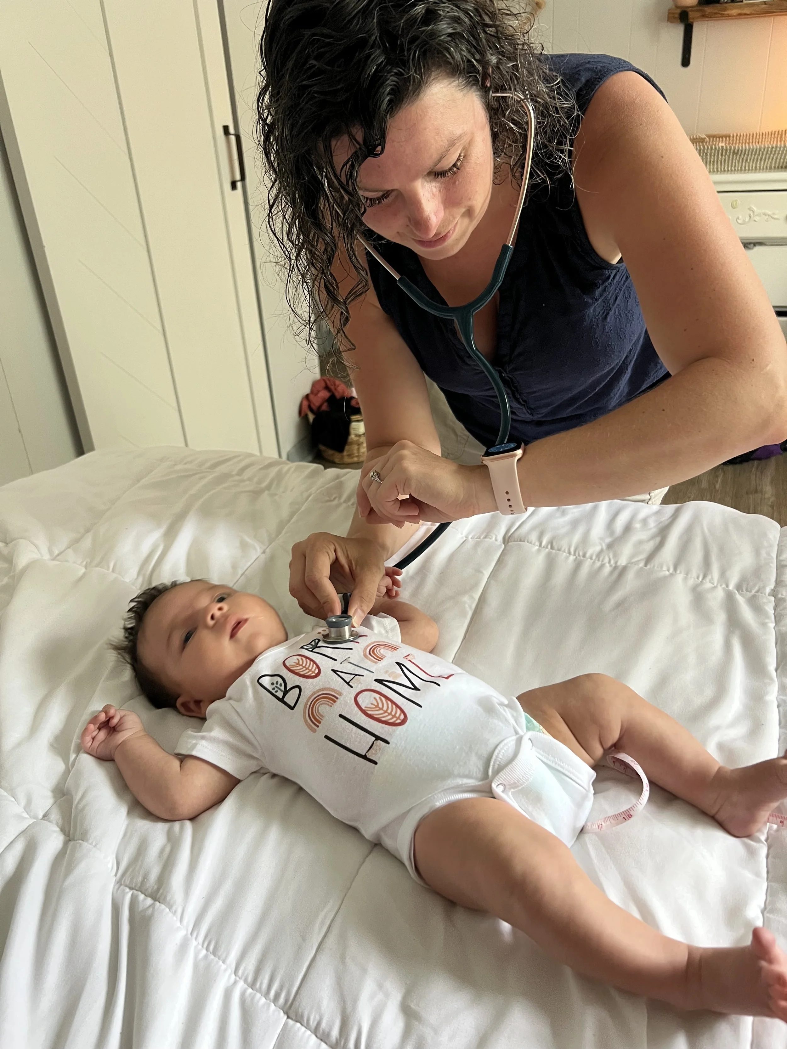 A homebirth midwife takes care of a mother and baby during a postpartum visit after their home birth.