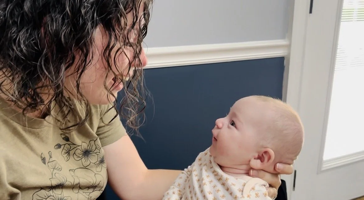 A home birth midwife is holding a newborn during a postpartum visit in Athens, TN