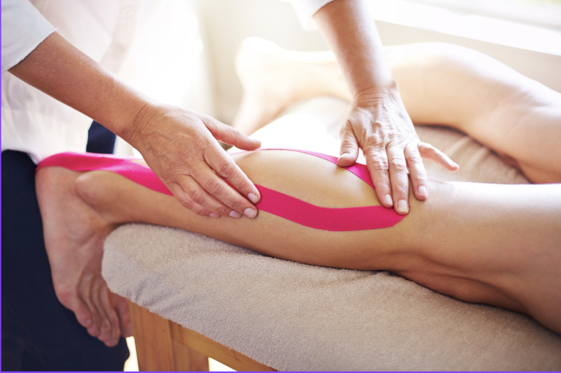Massage therapist applying kinesiology tape to a person's calf muscle during a treatment session.