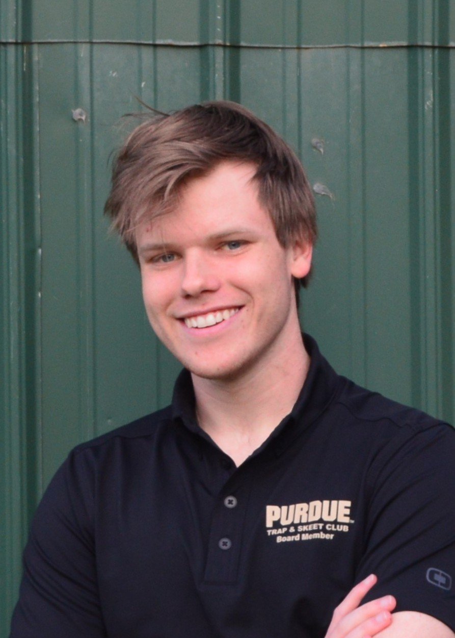 A person wearing glasses and a dark polo shirt with "Purdue Trap & Skeet" logo on it.