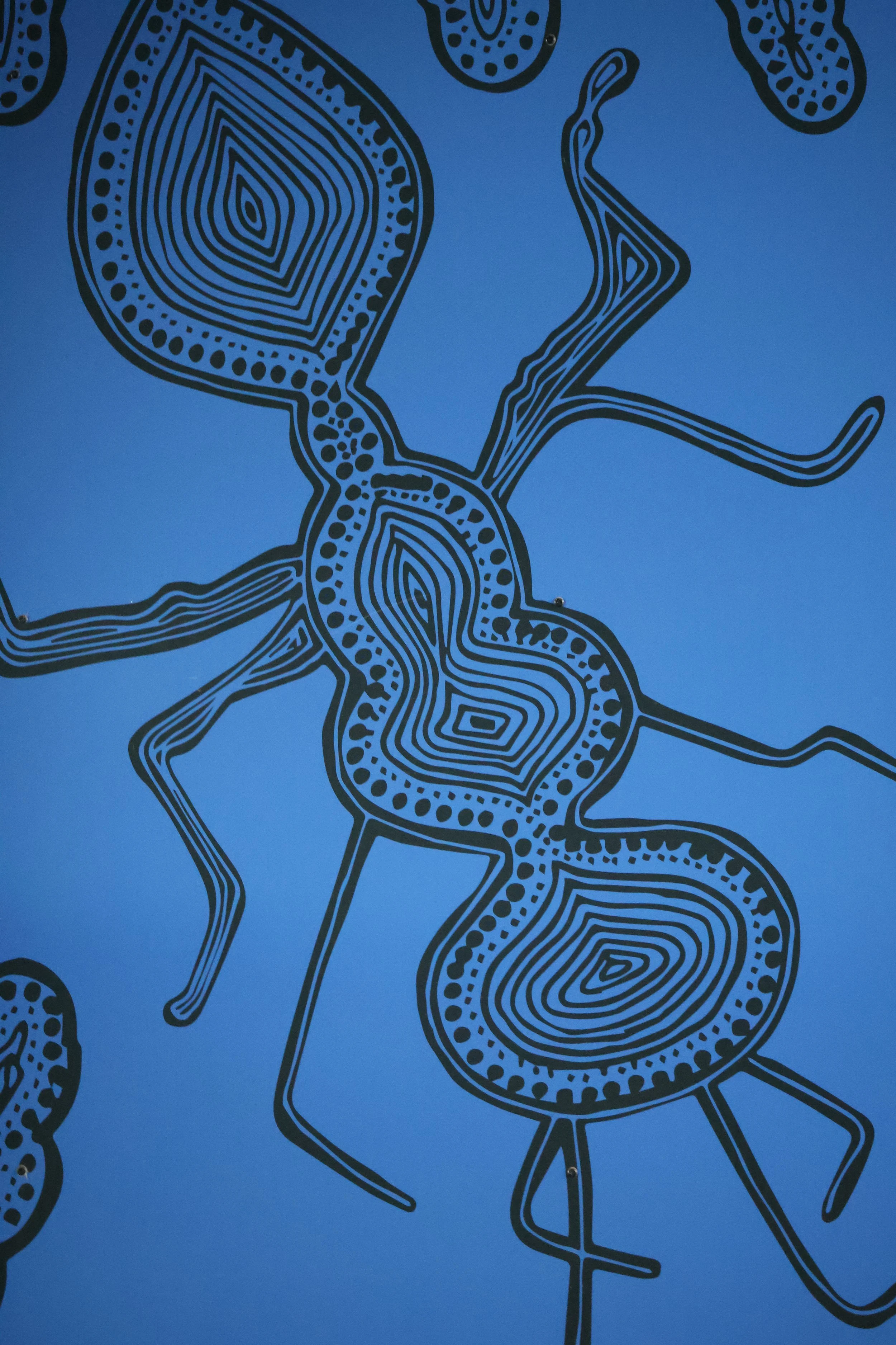 Blue wall with abstract line art of stylized ants and a door with silver handles.