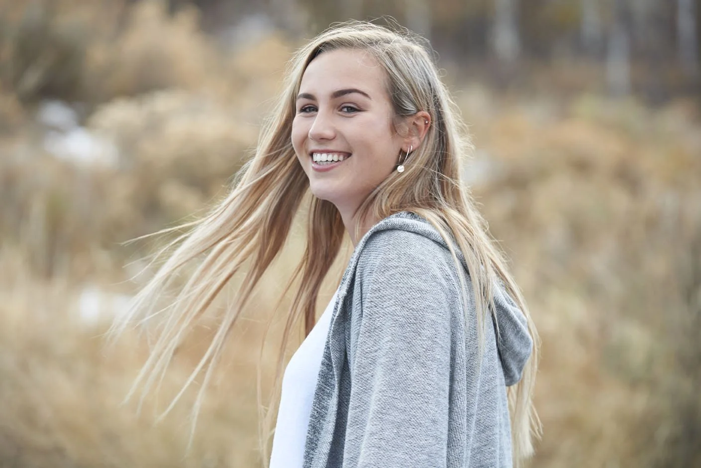 senior portrait girl in field smiling and swinging long hair