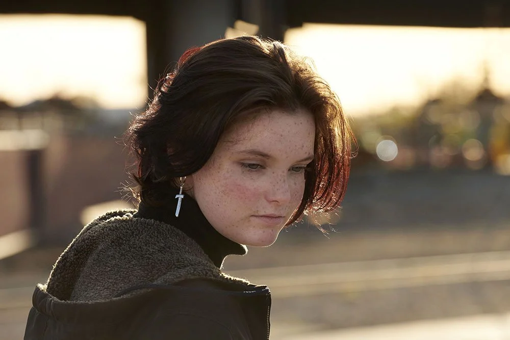 senior portrait of teen in dusk backlit streetscene