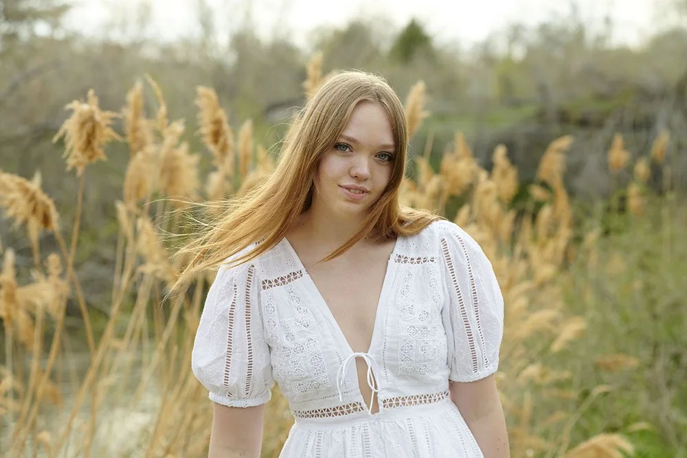 senior portrait teen girl walking in tall fall grasses near river