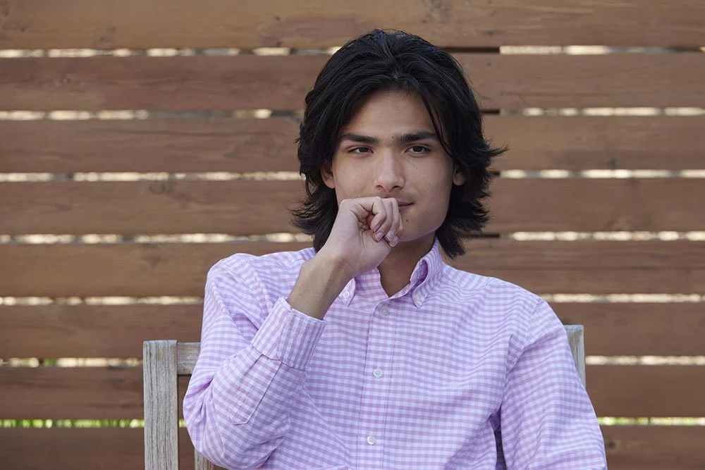 senior portrait of teen boy in pink check shirt thoughtful