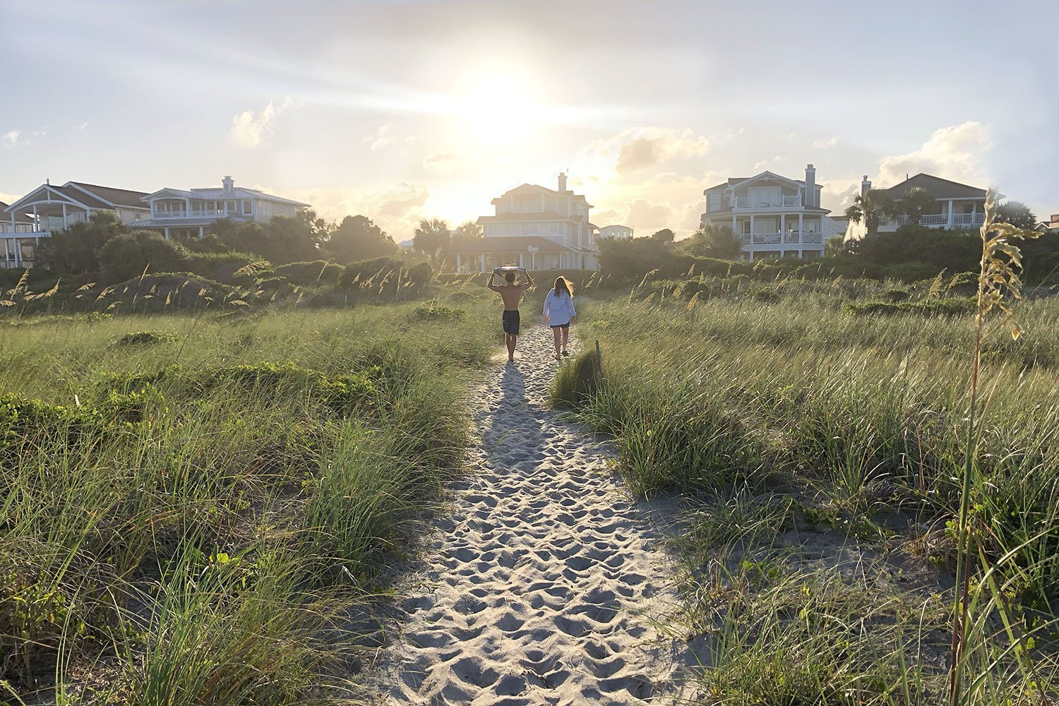 Kirsten Hepburn Photography portrait of surfer carrying board through beach grass in Wilmington