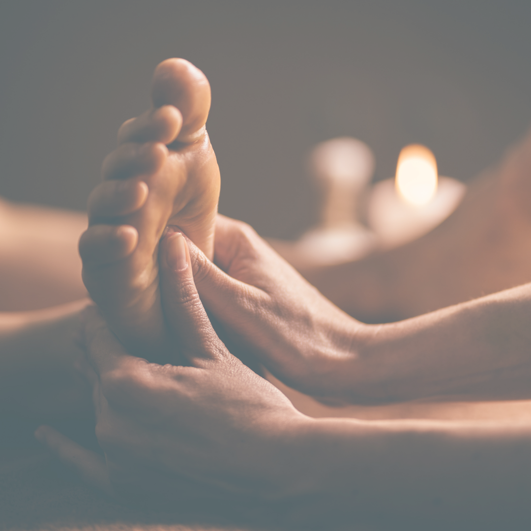 Close-up of a person receiving a hand massage in a spa setting, with candles in the background creating a relaxing atmosphere.