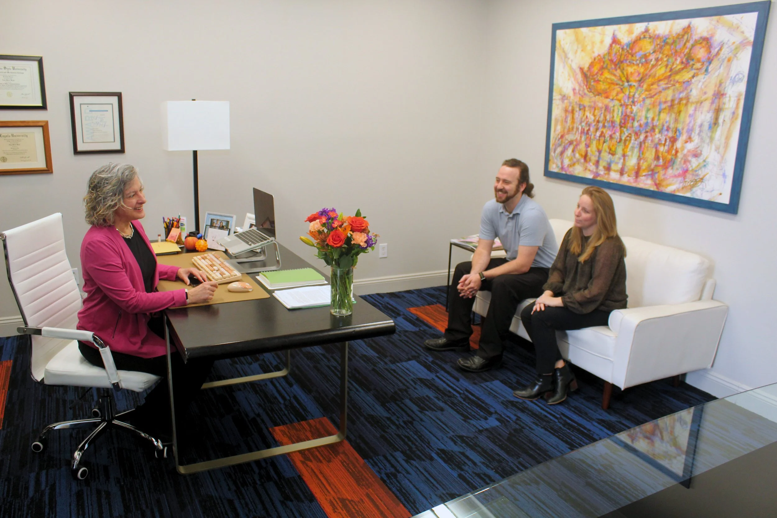 Three employees at Gambel Communications sit in an office and talk.