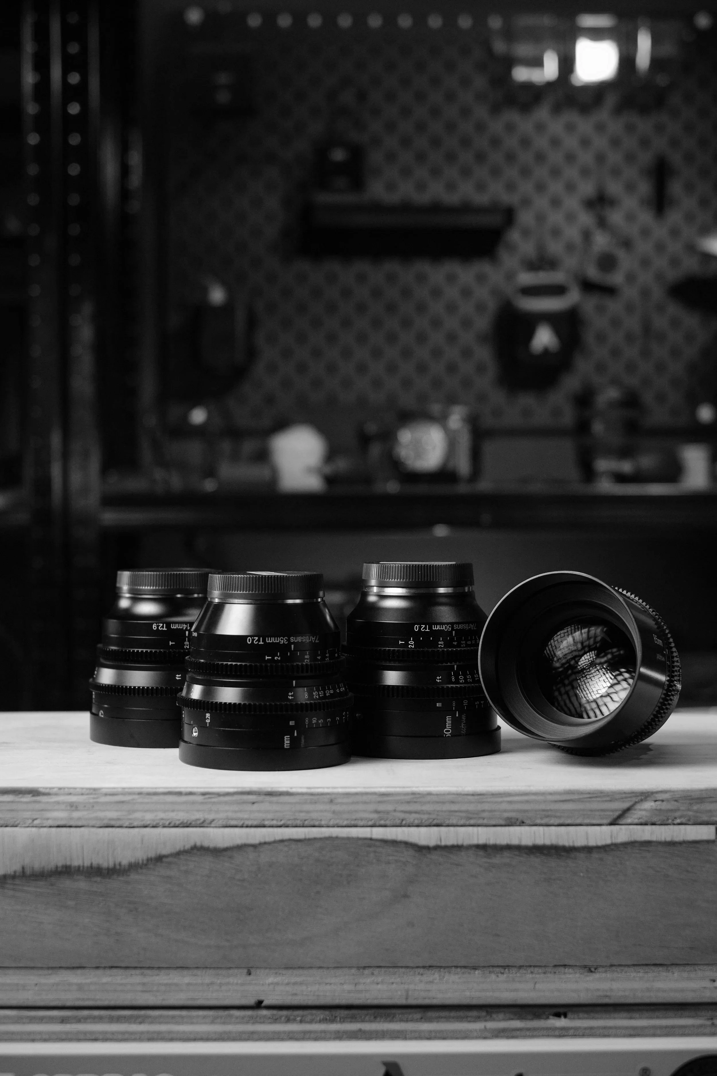Four camera lenses on a wooden surface with a blurred music stage background.