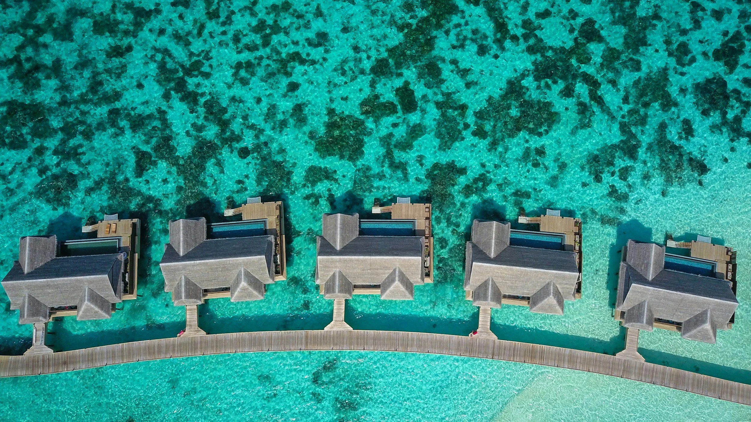 Luxury overwater villas in the Maldives surrounded by bright turquoise lagoon