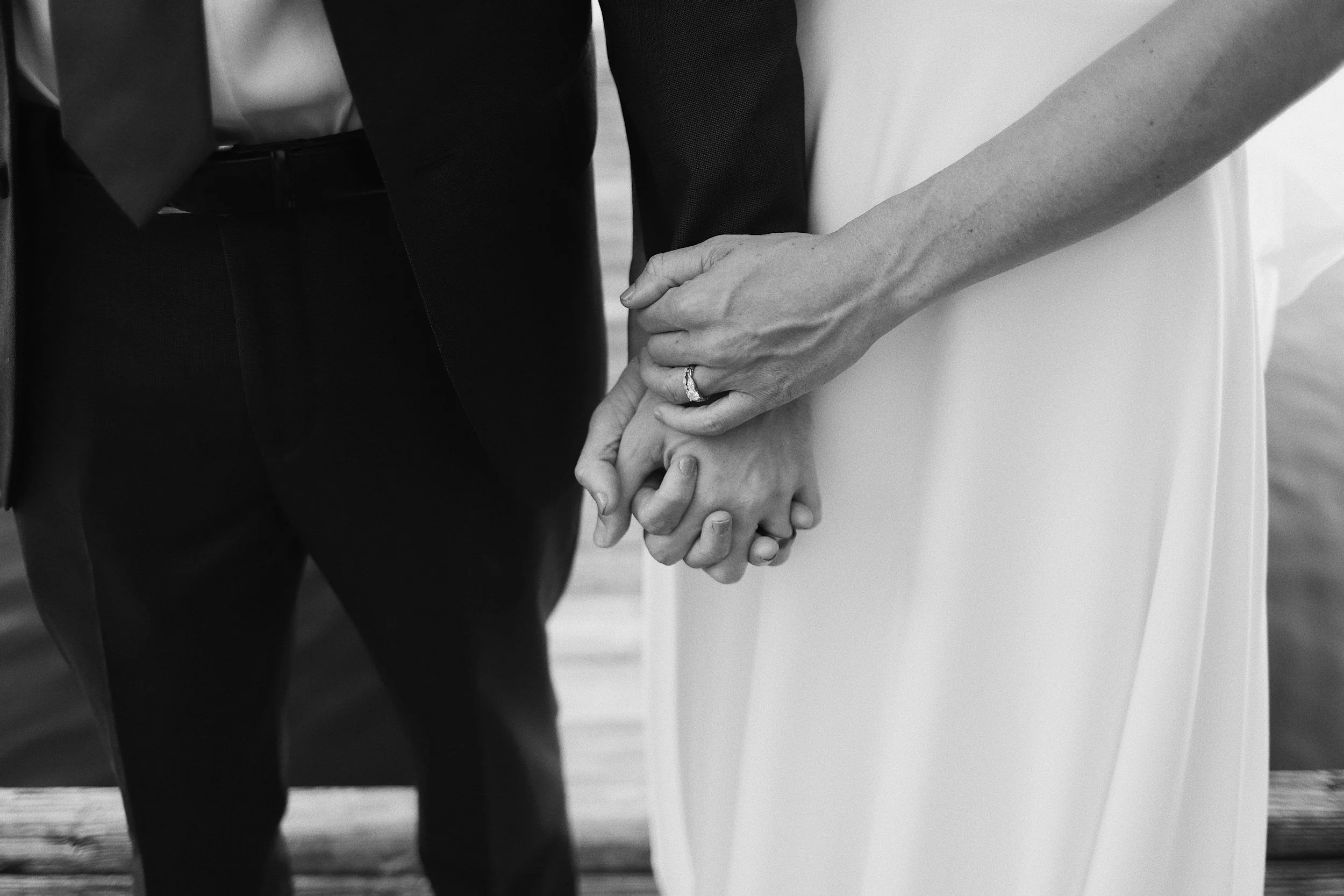 Black and white photo of wedding couple holding hands.