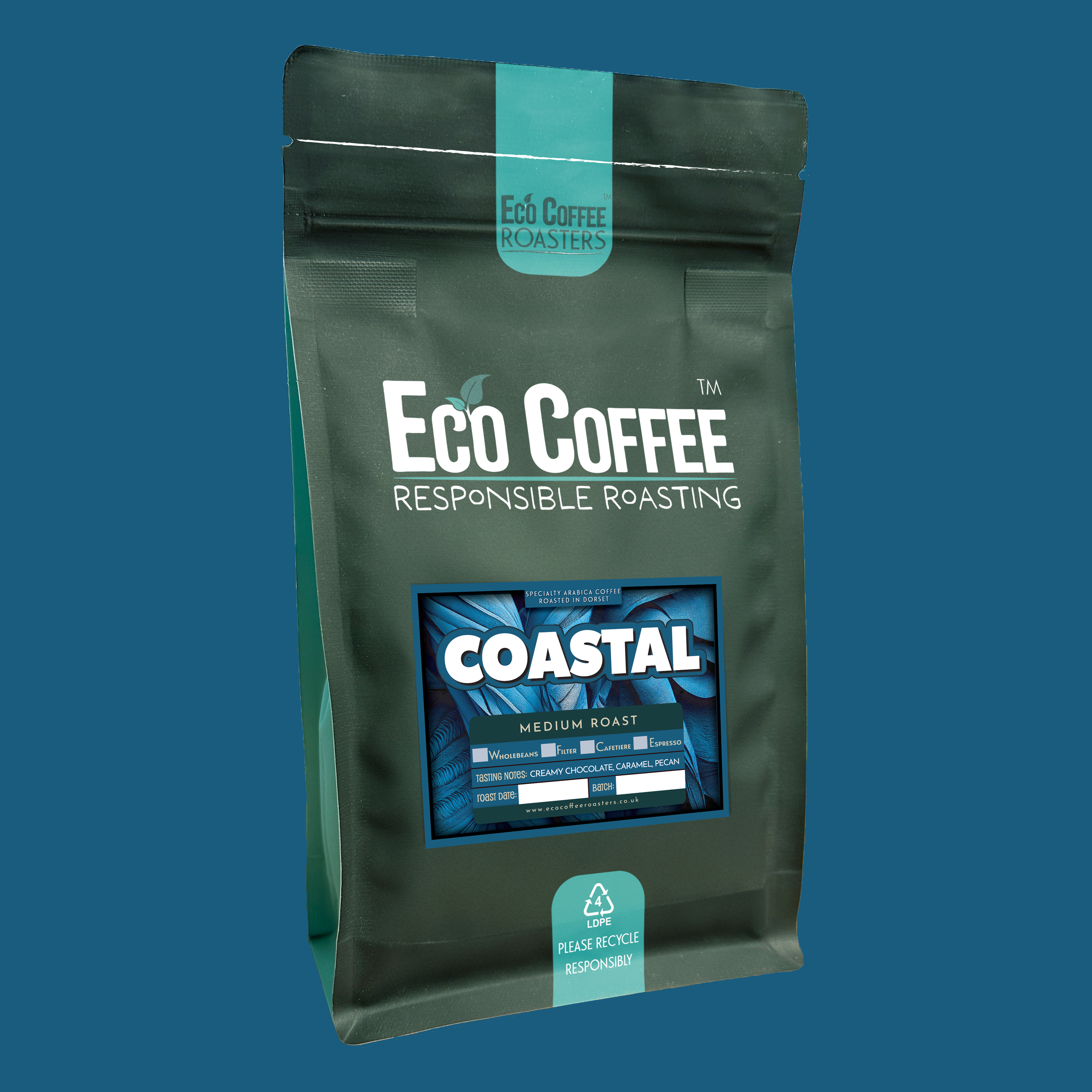 Eco Coffee Coastal Medium Roast package surrounded by pebbles and a blue curtain backdrop.
