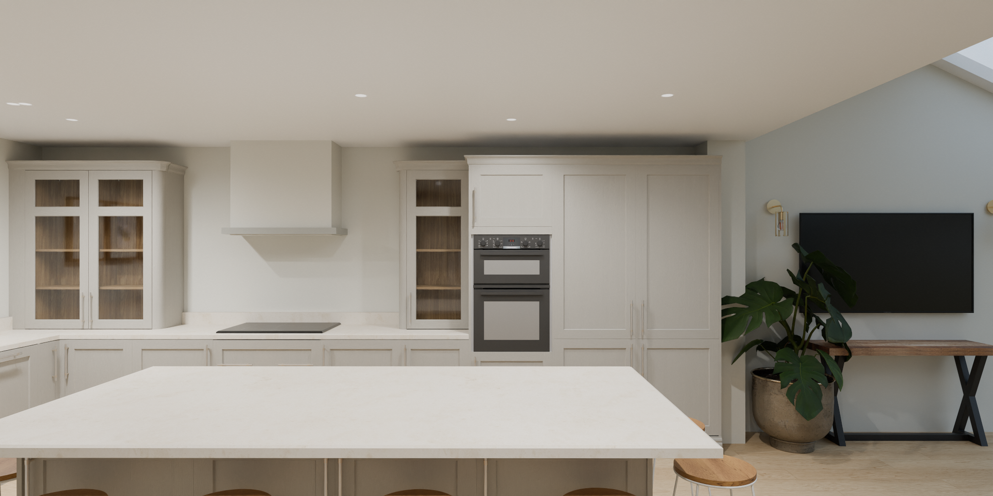 Modern kitchen with white cabinets, built-in oven, and a large white island with stools. A flat-screen TV is mounted on the wall next to a wooden desk with a potted plant.