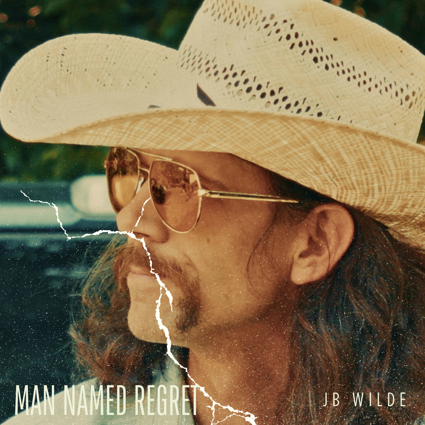 Close-up of a man wearing sunglasses and a wide-brimmed straw hat, with a torn and aged appearance, in a vintage-style photo.