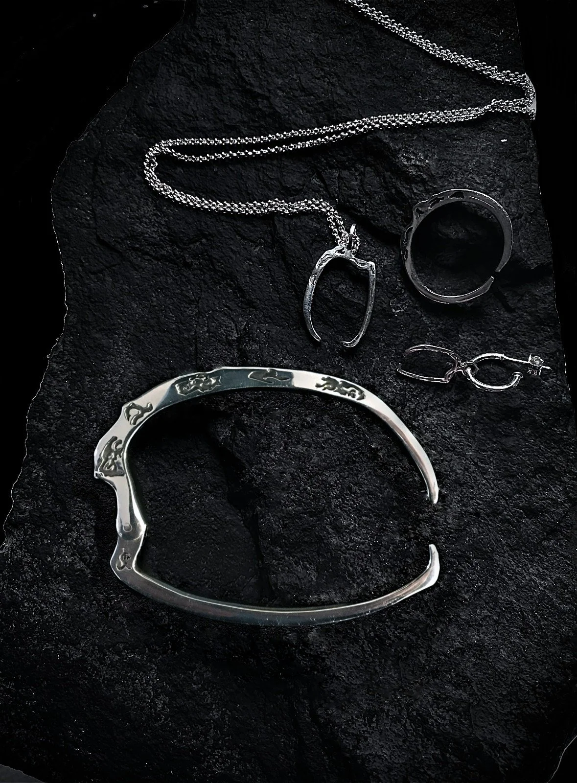 Skythe's Scythe jewellery collection on a dark textured surface
