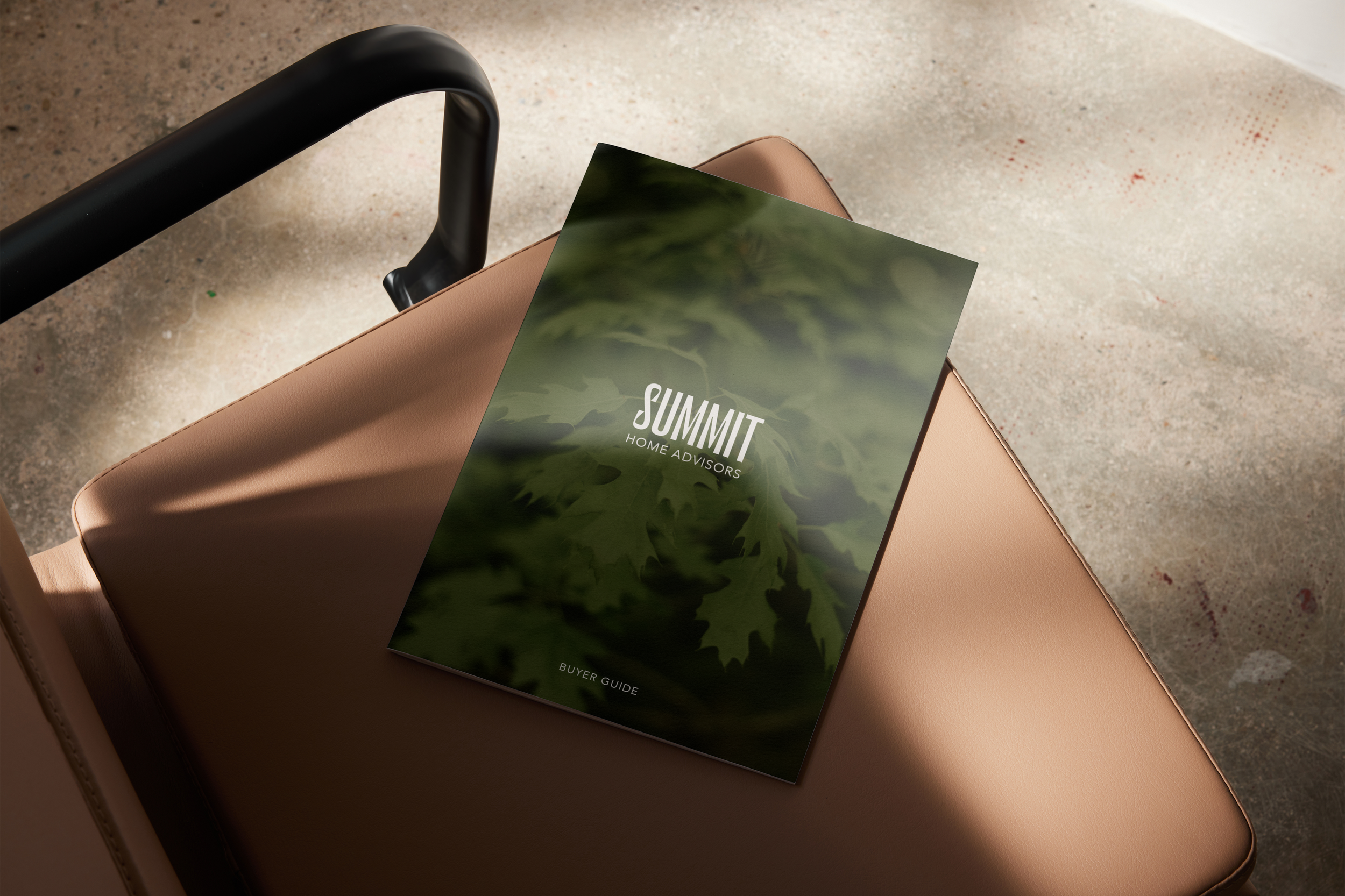 A brochure titled 'SUMMIT Home Advisors Buyer Guide' on a tan leather chair under natural light.