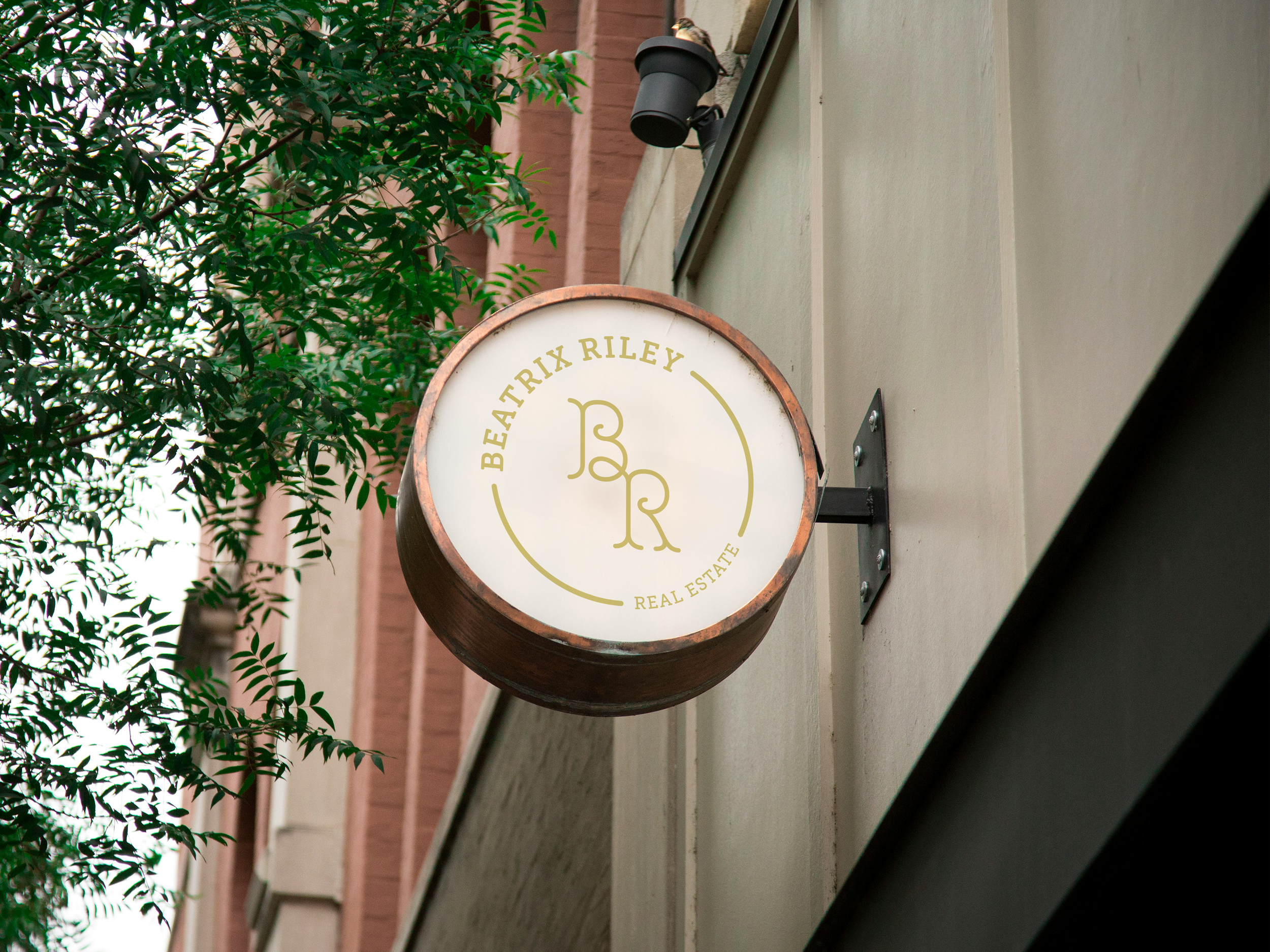 Round business sign with The Beatrix monogram logo on the outside of a building.