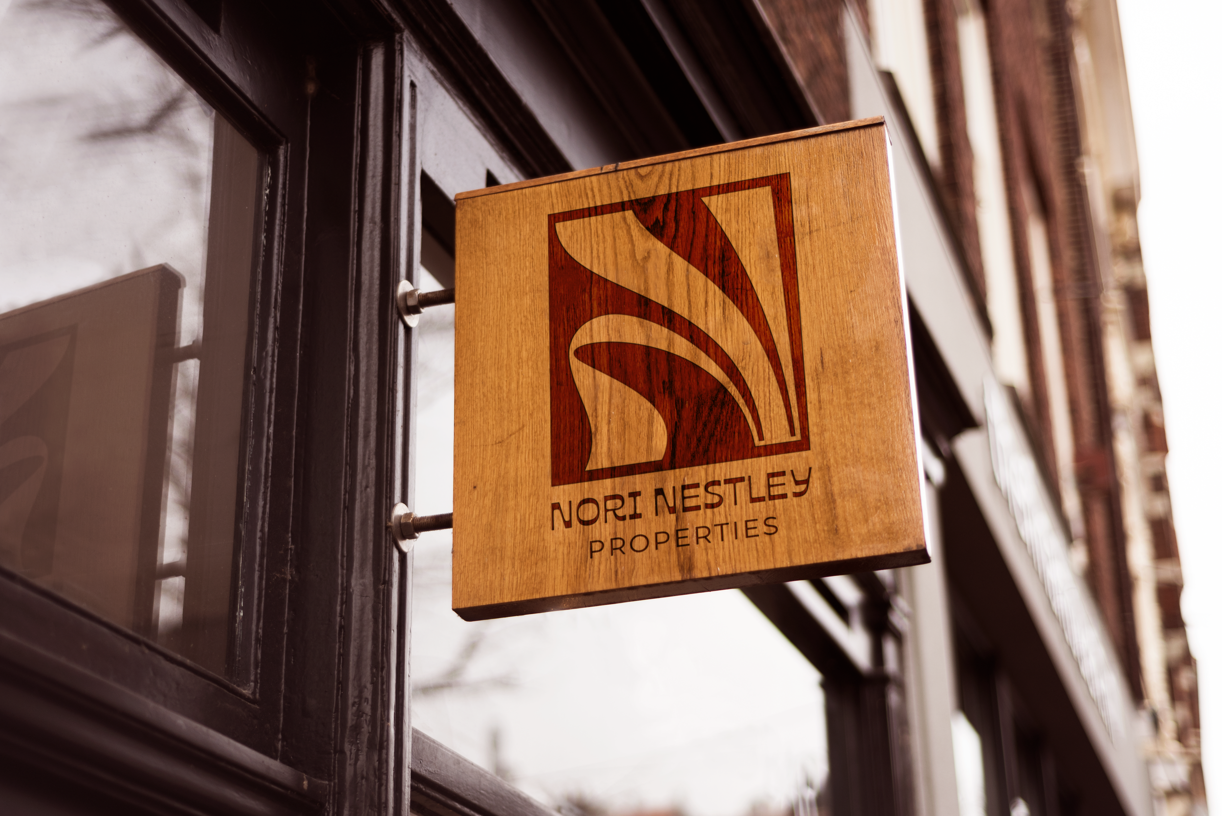Wooden business sign with The Nori monogram logo on the outside of a building.