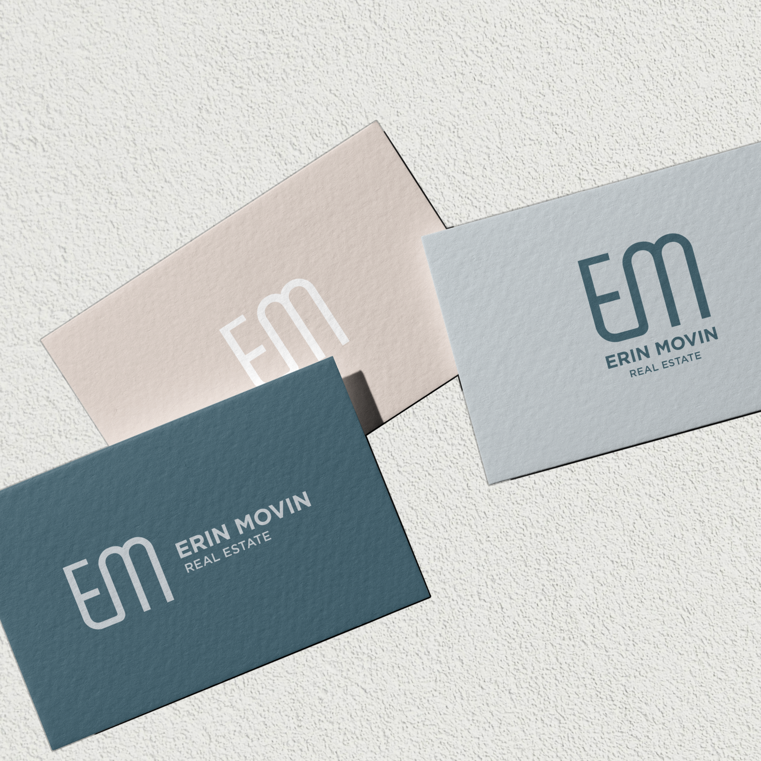 Three business cards with "EM Erin Movin Real Estate" logo in different colors on textured background.