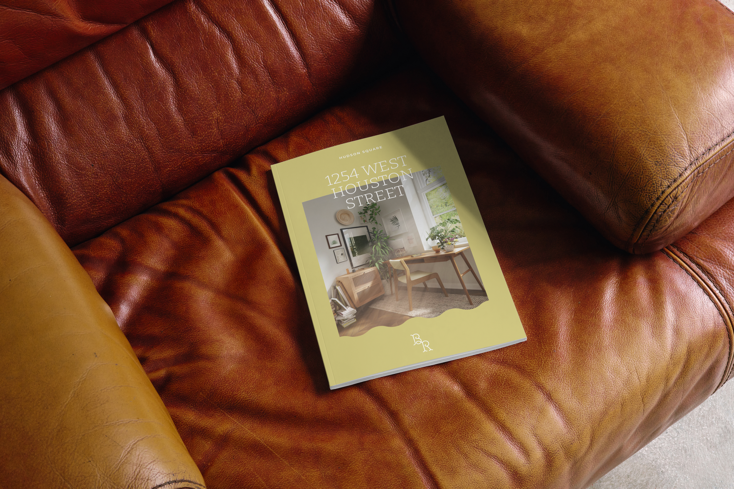 Real estate brochure labeled "1254 West Houston Street" on a brown leather sofa.